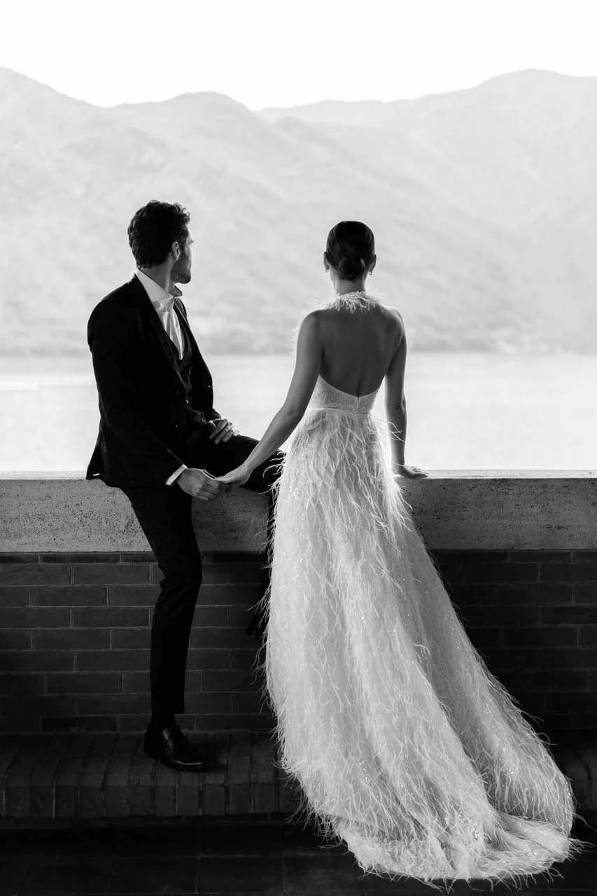 Editorial destination wedding photography: Bride and groom overlooking the serene waters of Lake Como, Italy, with a breathtaking mountain backdrop. 