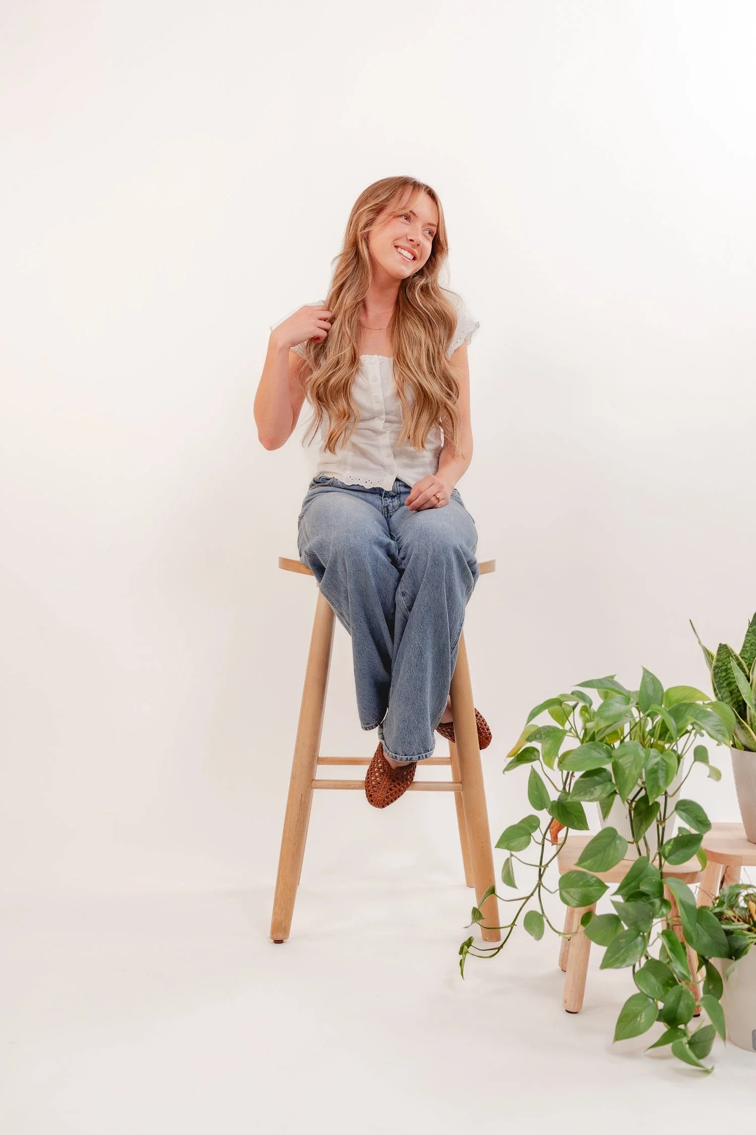 Ayden Crawford sitting on a wooden stool in a white top and jeans, Missouri State University, Happyologie student interview