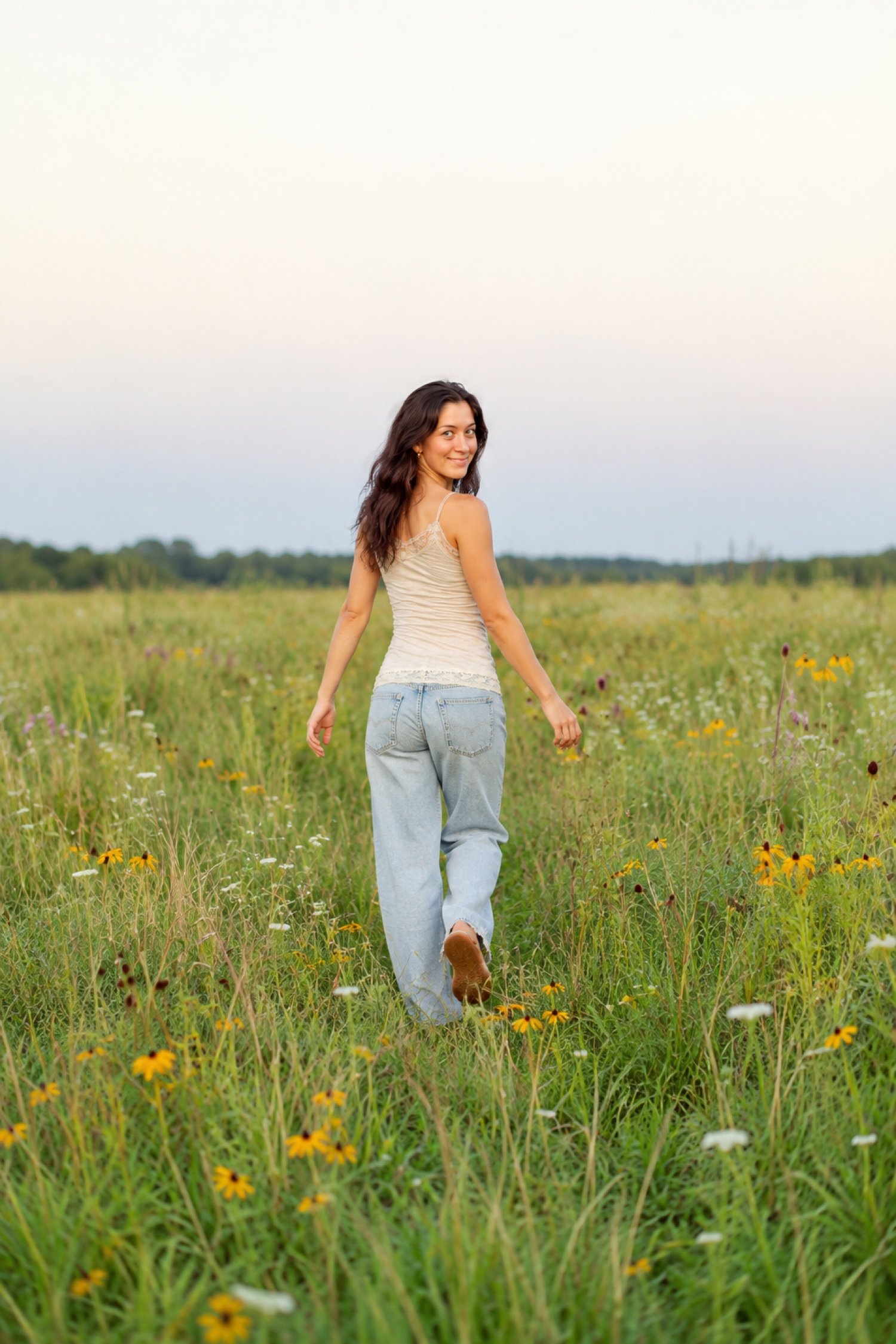 A woman walks through a field of yellow flowers.