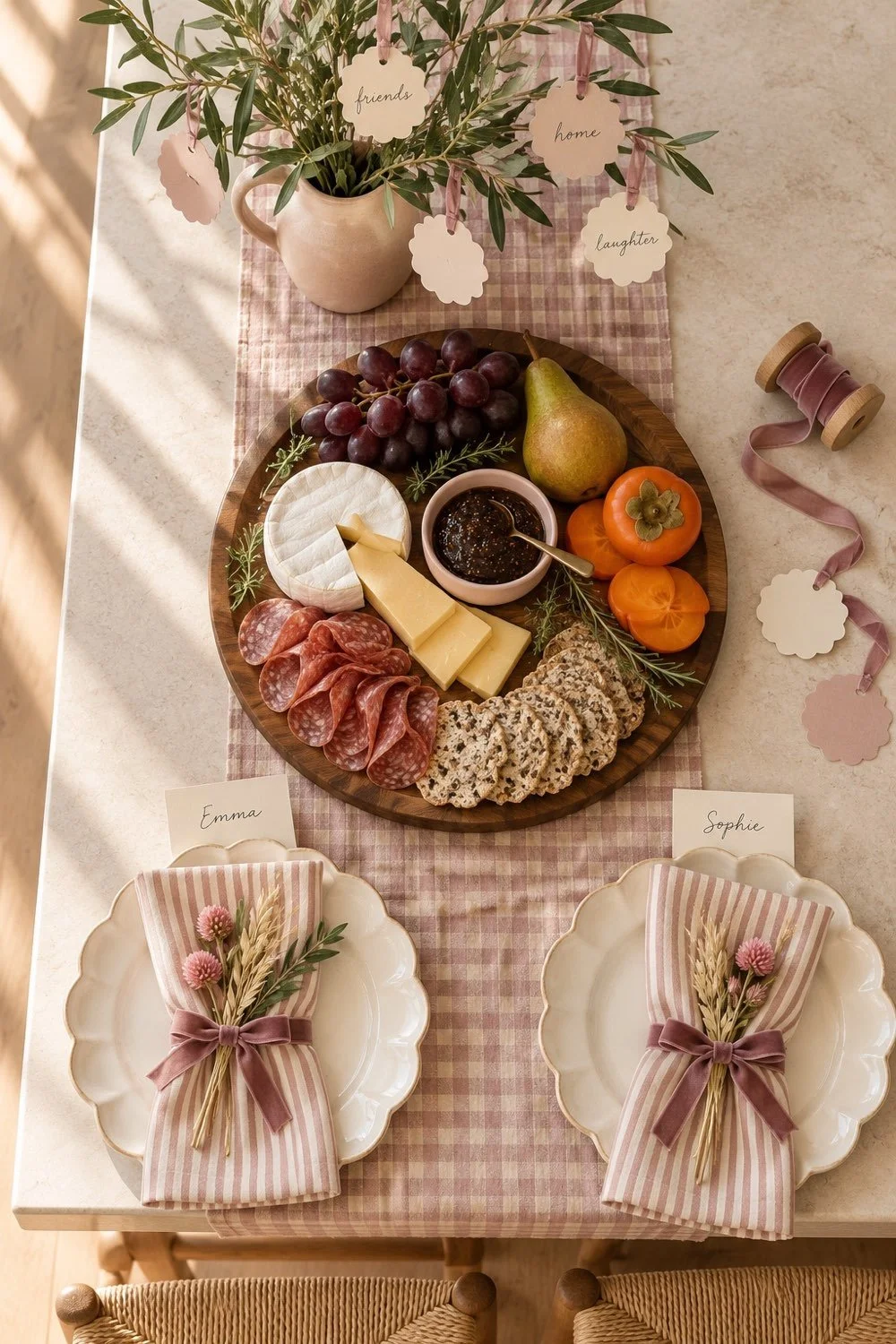 An overhead view shows a gratitude tree, snack board, and two blush striped napkins on a gingham runner.