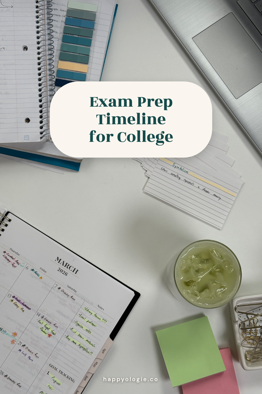 Overhead study desk with a notebook, flashcards, laptop, planner, and iced green drink.