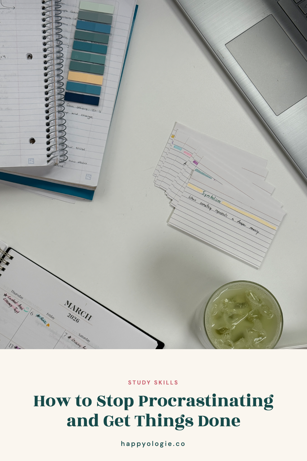 Study desk with notebook, flashcards, laptop, planner, and iced green drink.