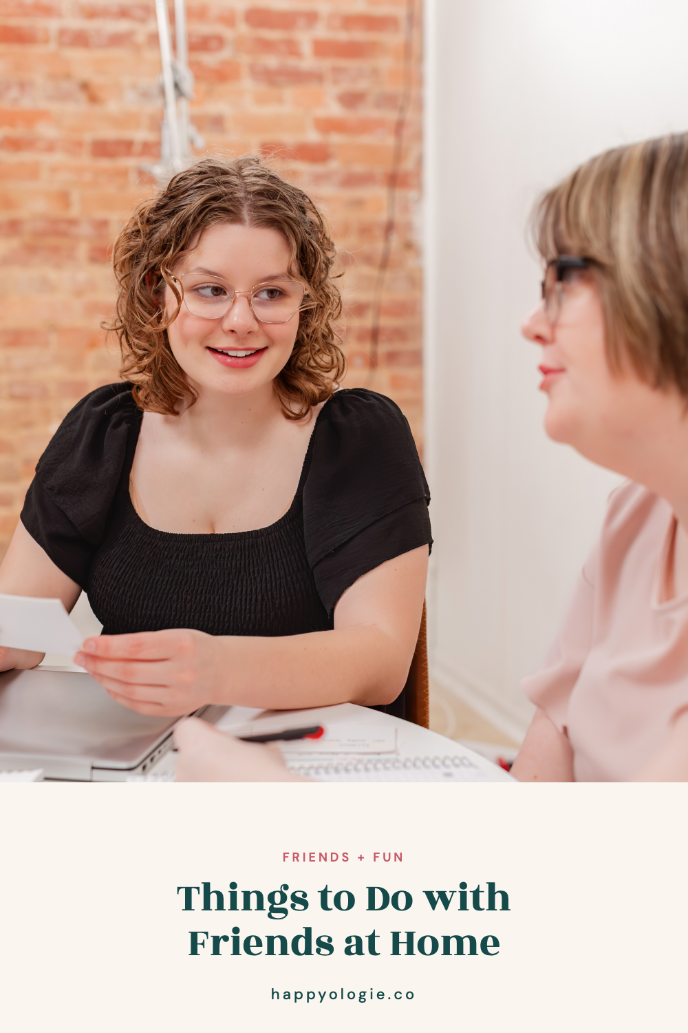 Two college students talking together beside a laptop and notebook.