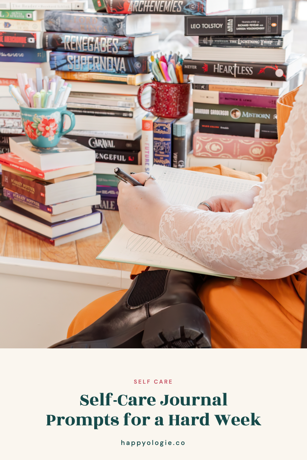 Student writing in a journal beside colorful pens and stacks of books.