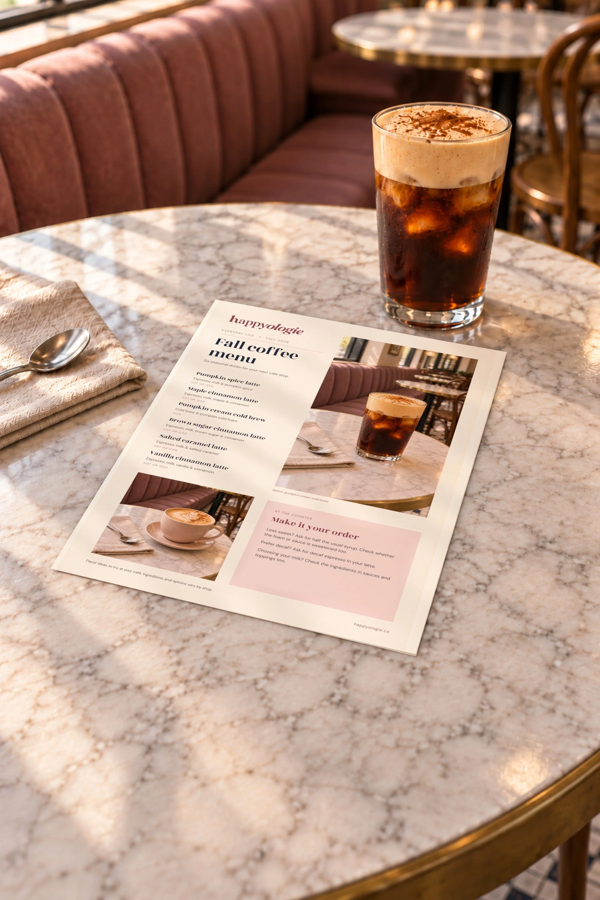 Happyologie Fall Coffee Menu on a marble café table beside pumpkin cream cold brew.