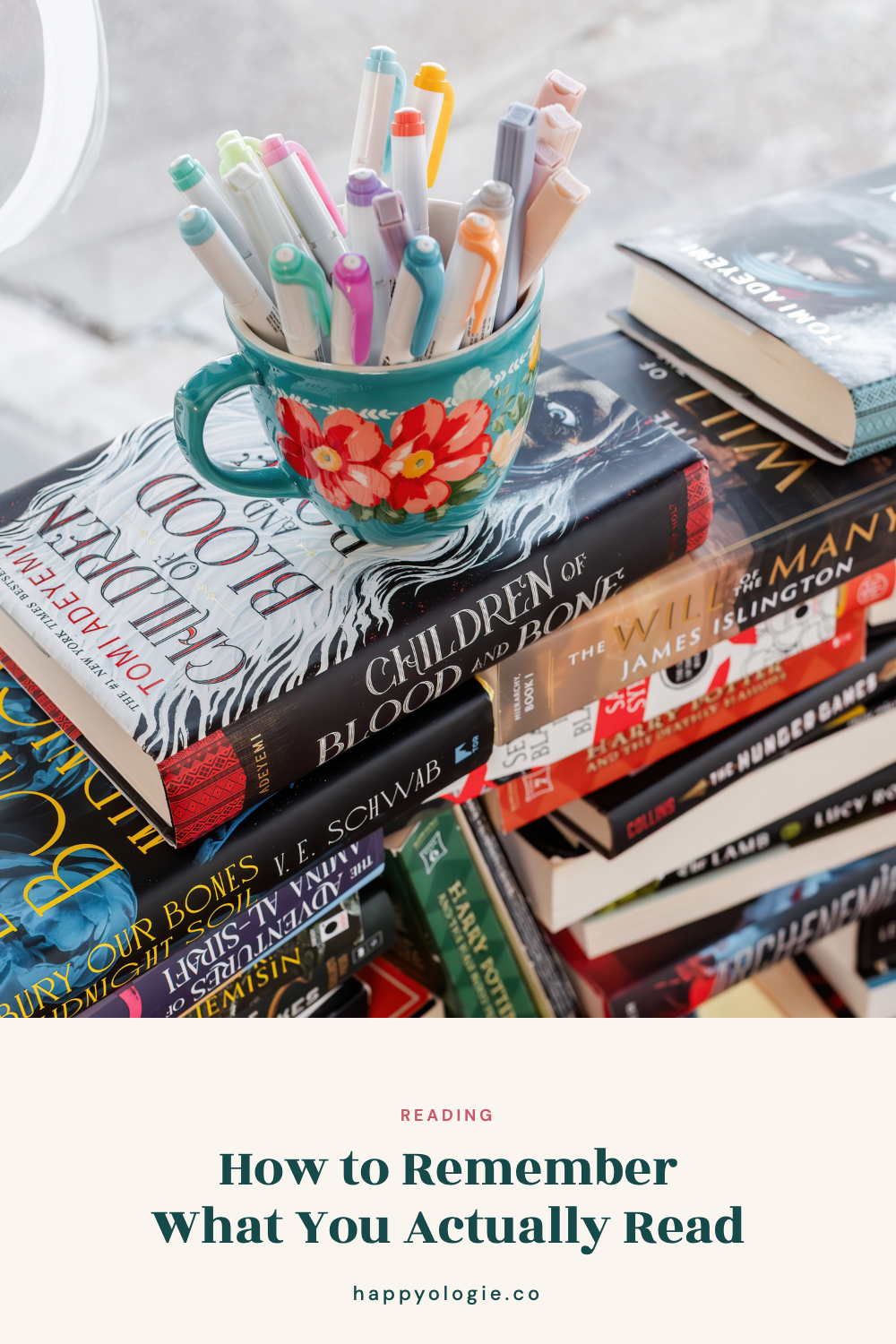 Colorful pens in a floral mug resting on a stack of books.