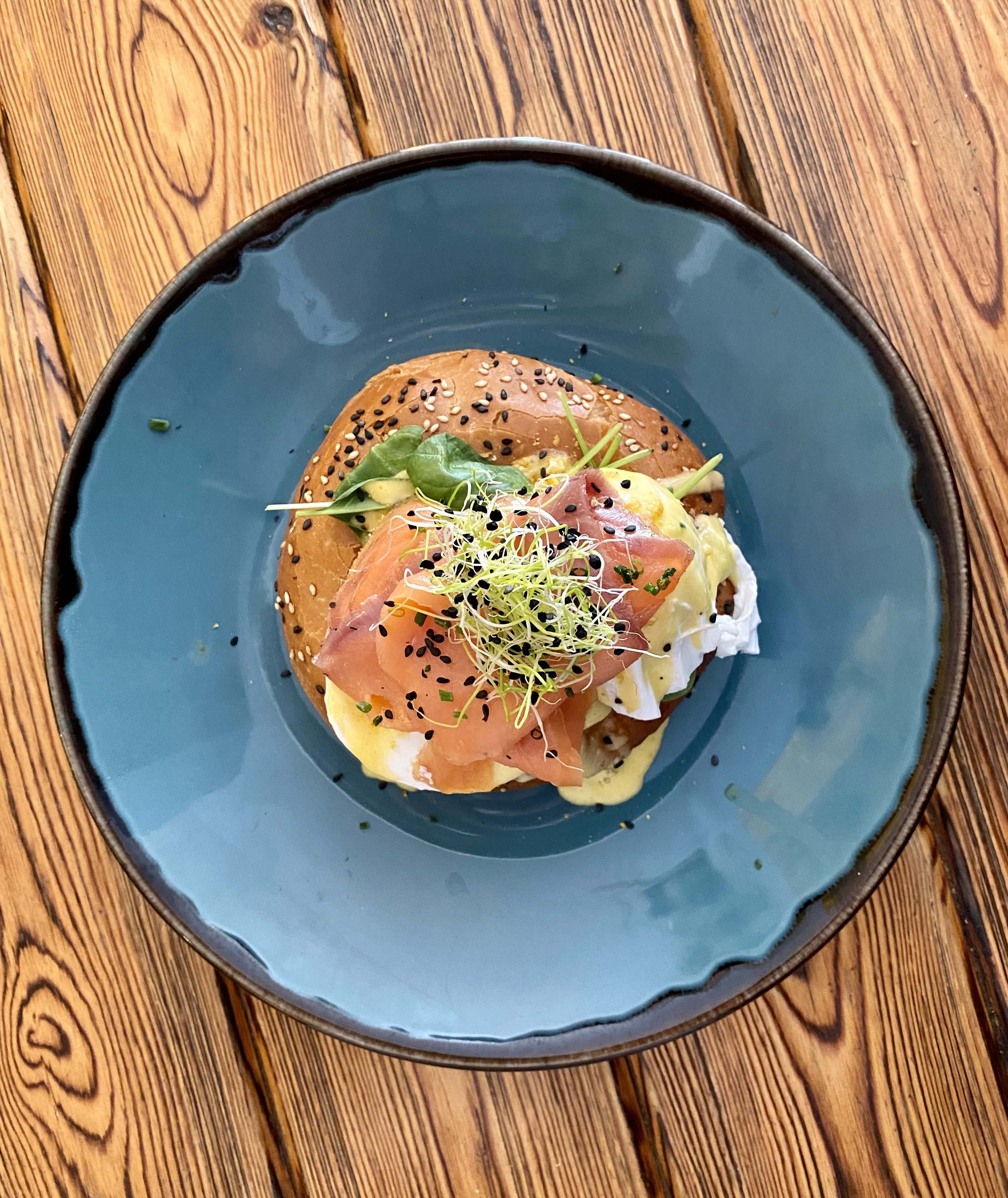 Tostada con aguacate, huevos pochados, jamón, germinados y semillas de sésamo.