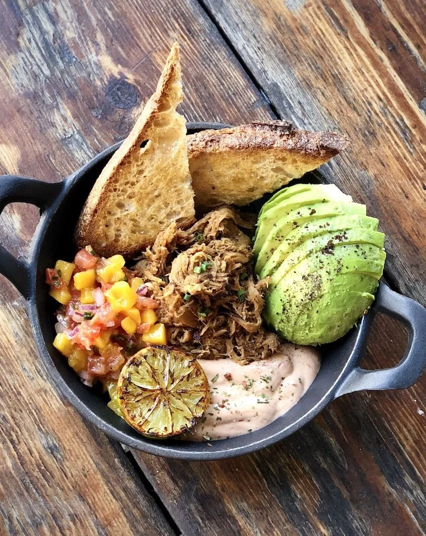 Panchito con tostadas de pan, carne de res deshebrada, aguacate en rodajas con pimienta, salsa de maíz y jitomate, limón asado, pimienta y crema.