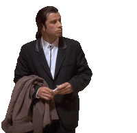 Man with brown hair wearing a black blazer and white shirt, holding a coat, standing against a brown background.