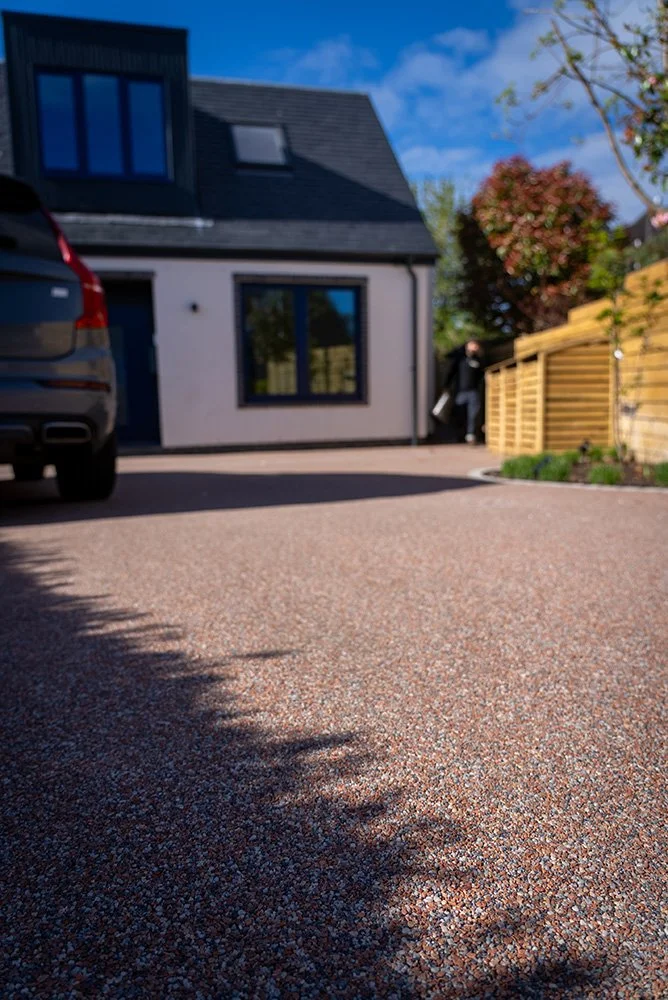 Photo of a house with a new brick red coloured resin driveway on a sunny day.