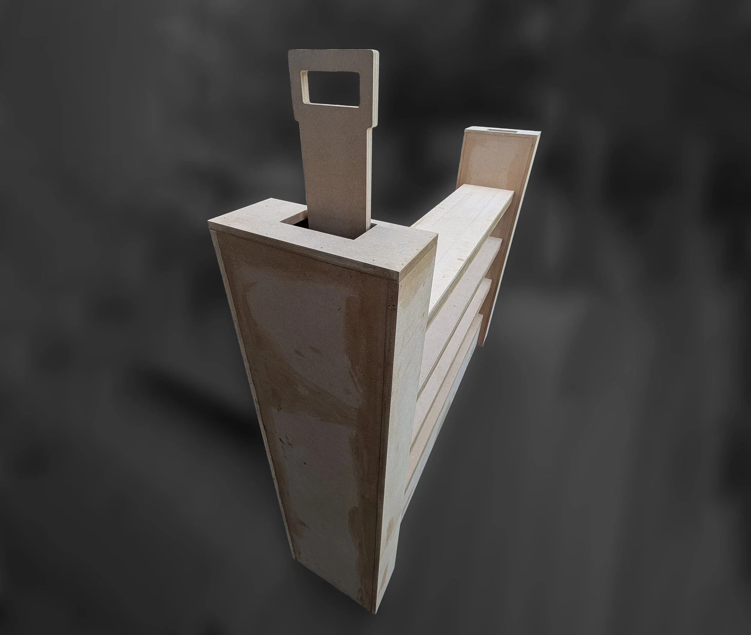 A sculpture of a vintage computer monitor and a keyboard, made from wood or similar material, with a minimalist design, set against a dark background.