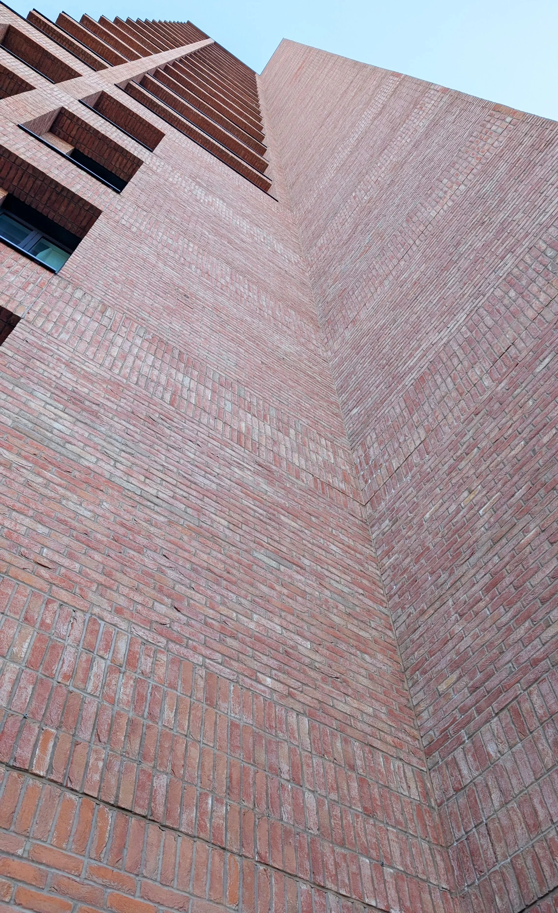 Low angle view of a brick building's corner with a blue sky background.