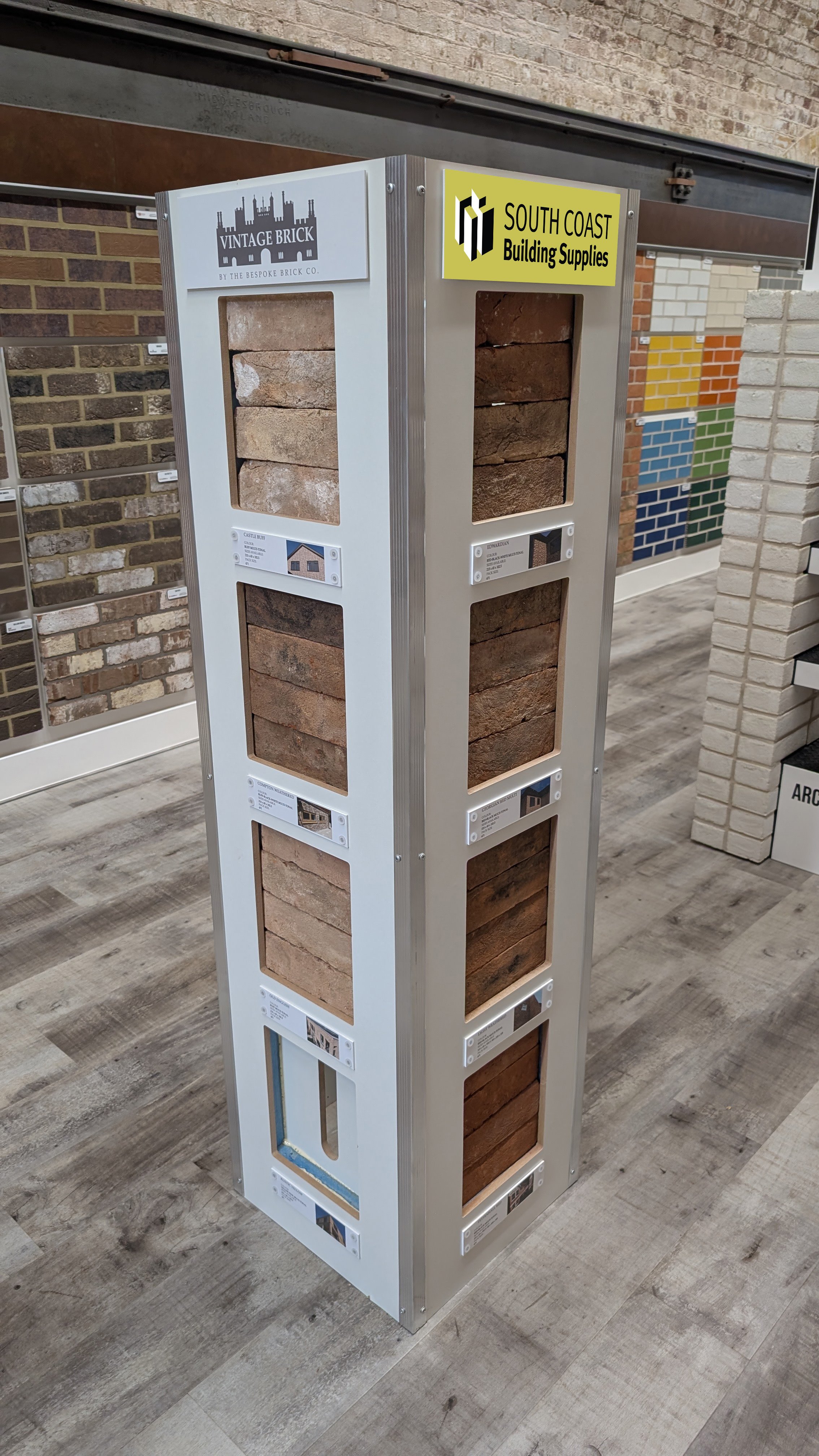 Display stand showcasing various types of bricks with labels and brand logos in a building supplies store.