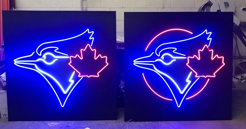 Two neon signs depicting a bird head with a maple leaf, one with a circular background and the other without.