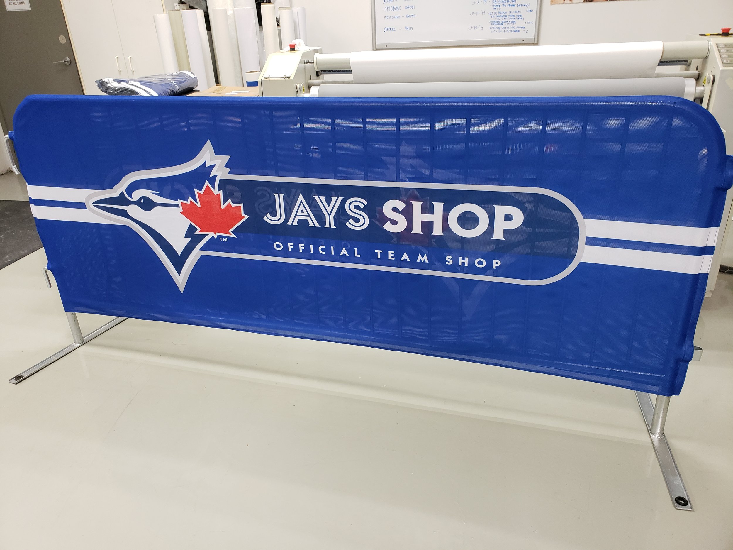 A blue banner with the Toronto Blue Jays logo and text that reads 'Jays Shop, Official Team Shop' in an indoor setting.