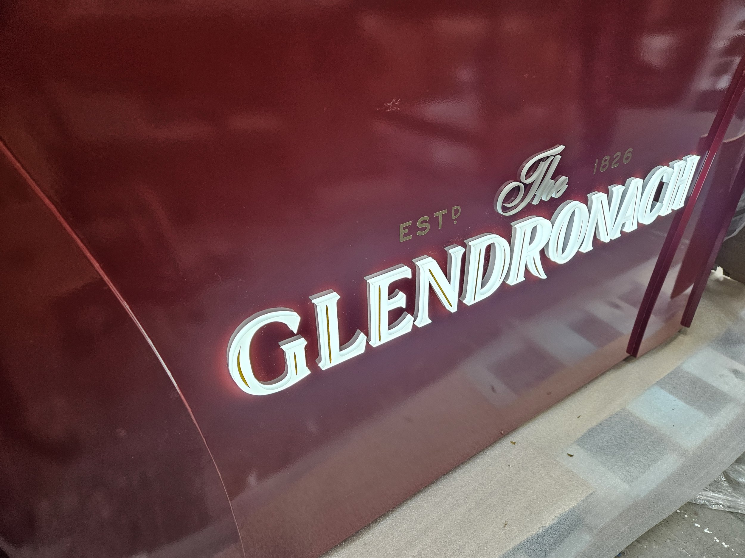 Close-up of a maroon-colored sign with illuminated white lettering that reads 'The Gilmore' and smaller text 'ESTD 1826' above it.