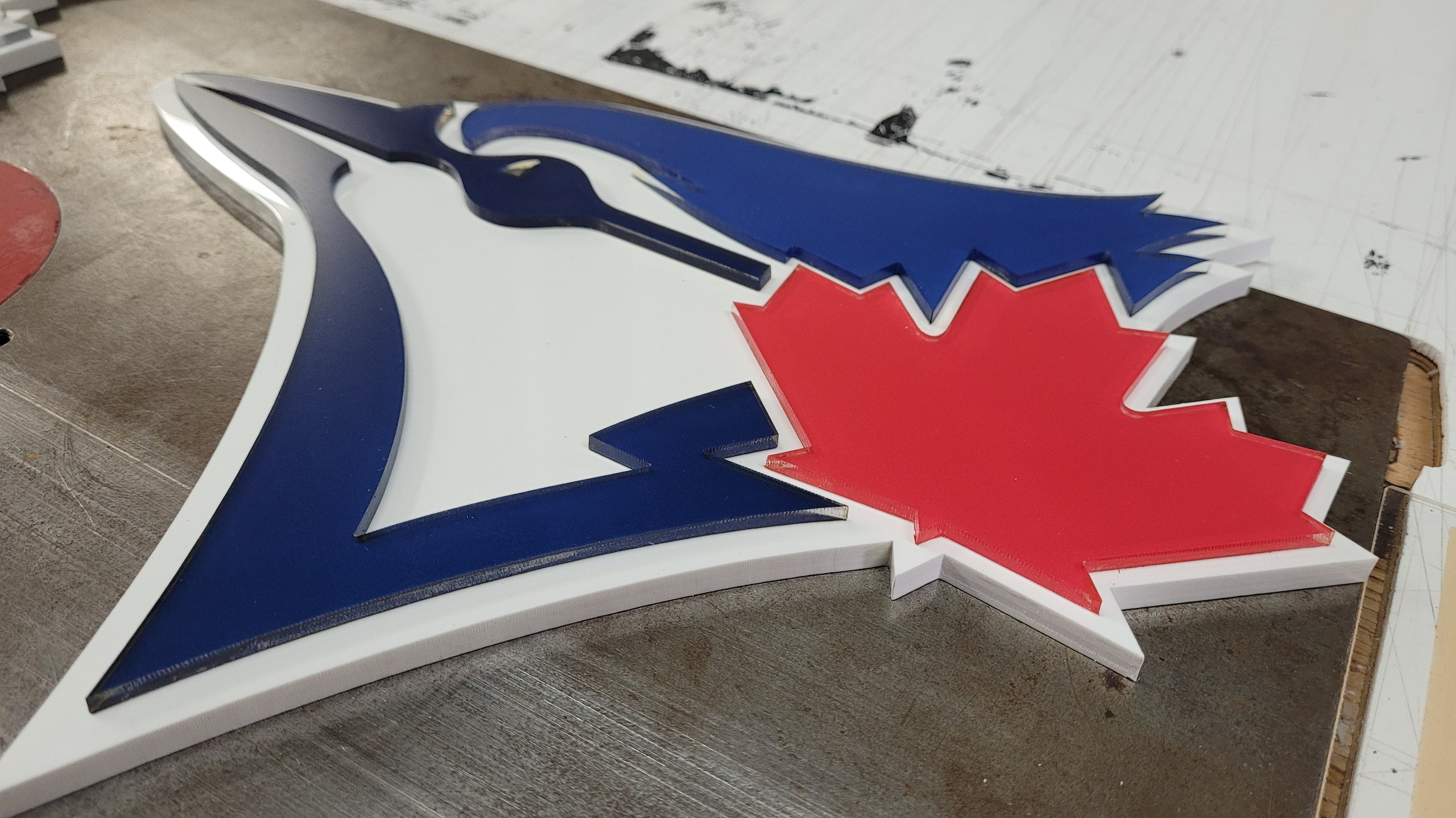 A three-dimensional logo featuring a white horse head with a blue mane, a red maple leaf, and a blue outline, resting on a workbench.