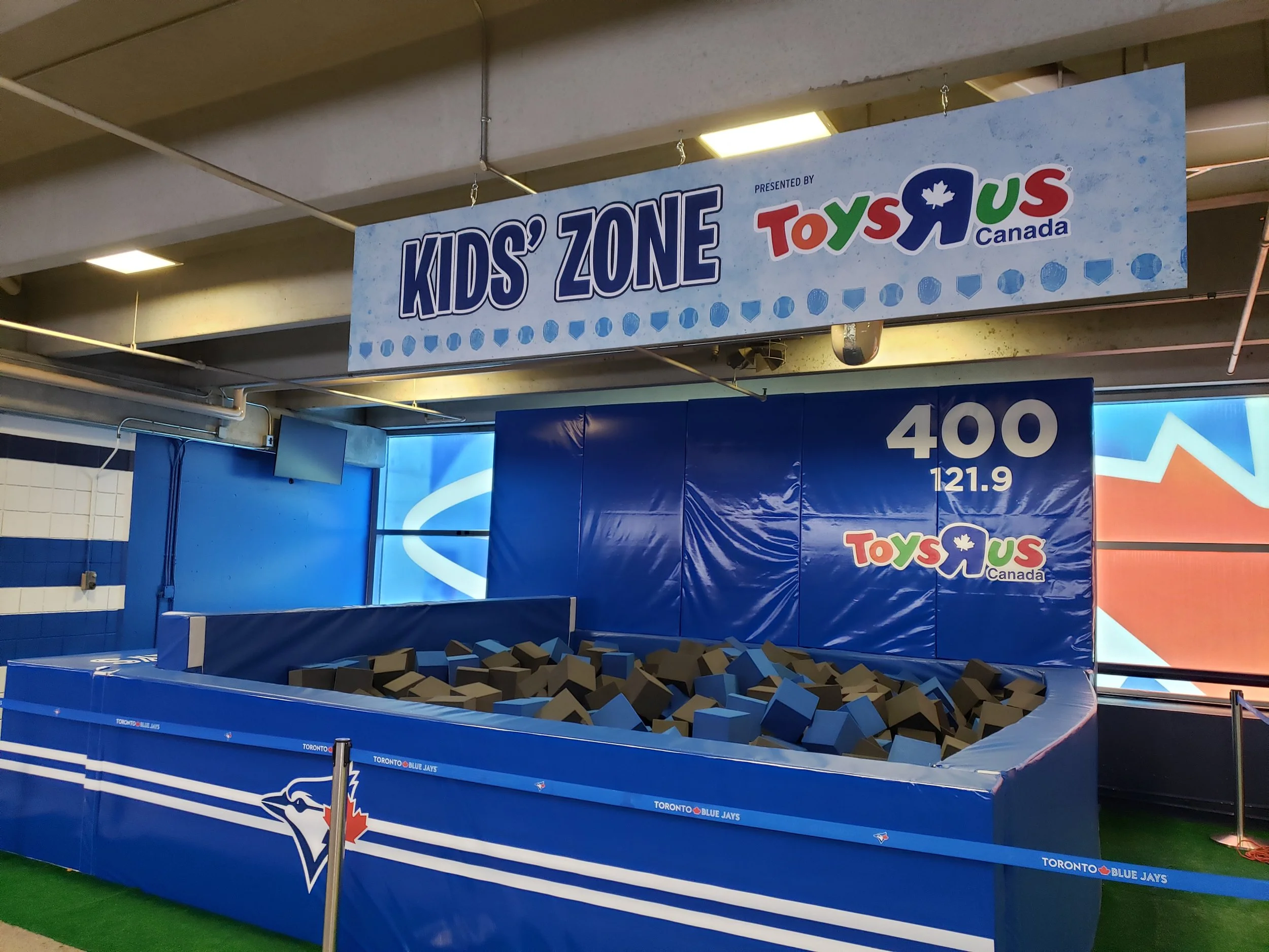 Kids' zone with a foam pit filled with blue and brown foam blocks, featuring Toronto Blue Jays branding and a sign for Toys R Us Canada.
