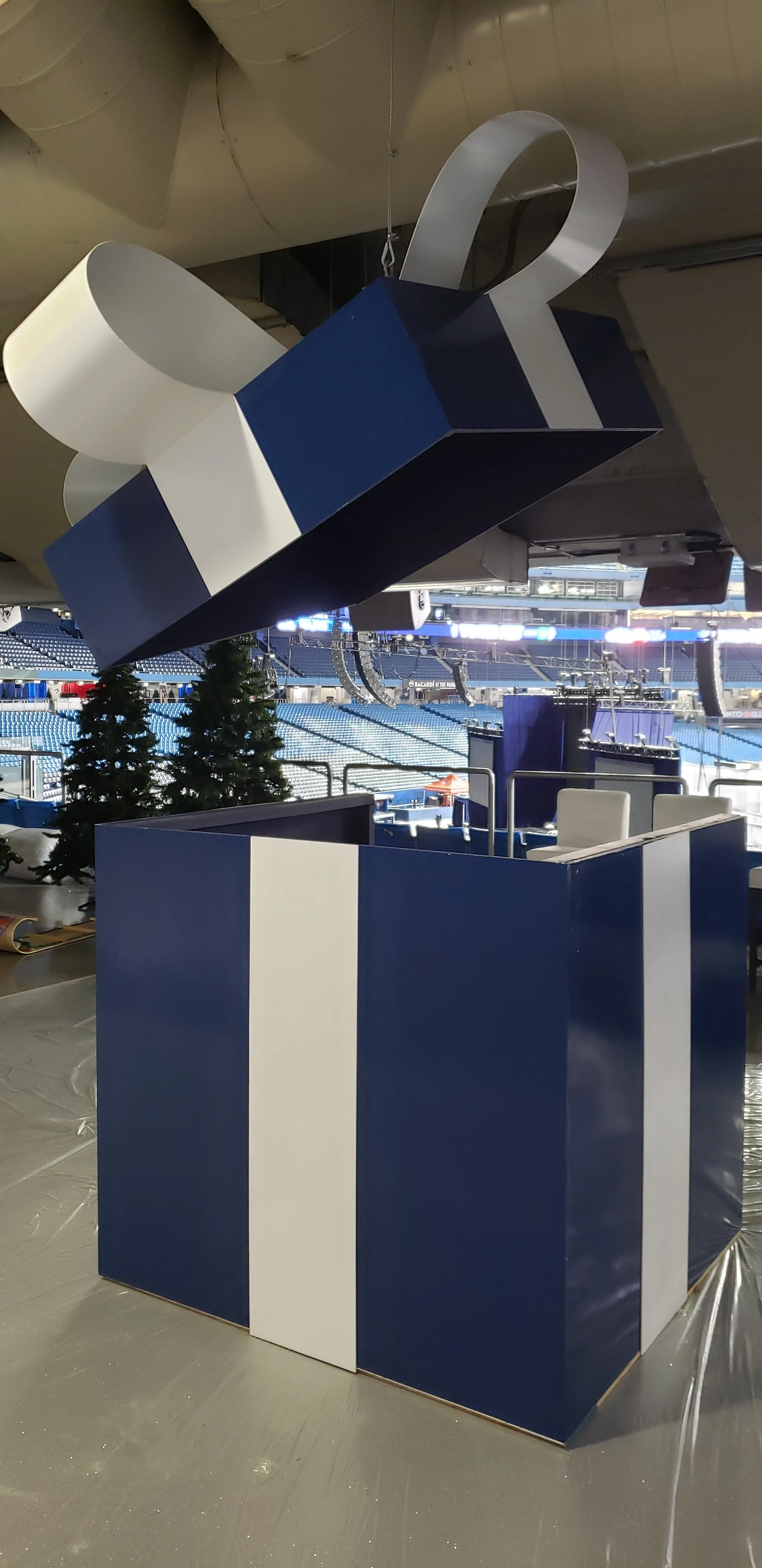 A large blue and white gift box with a ribbon and bow hanging upside down, suspended from the ceiling.