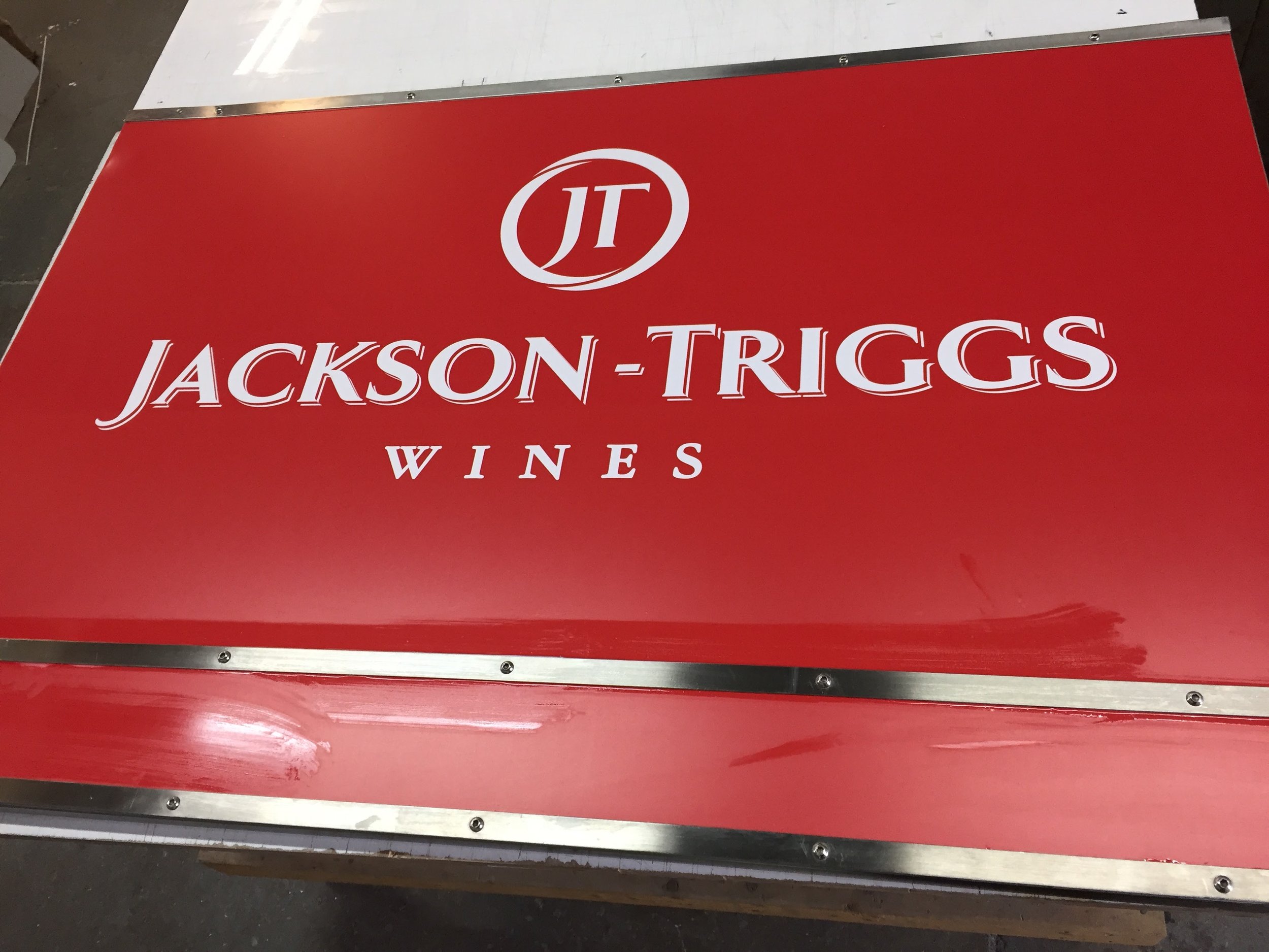 Red and white sign for Jackson-Triggs Wines with a logo featuring the initials 'JT'.