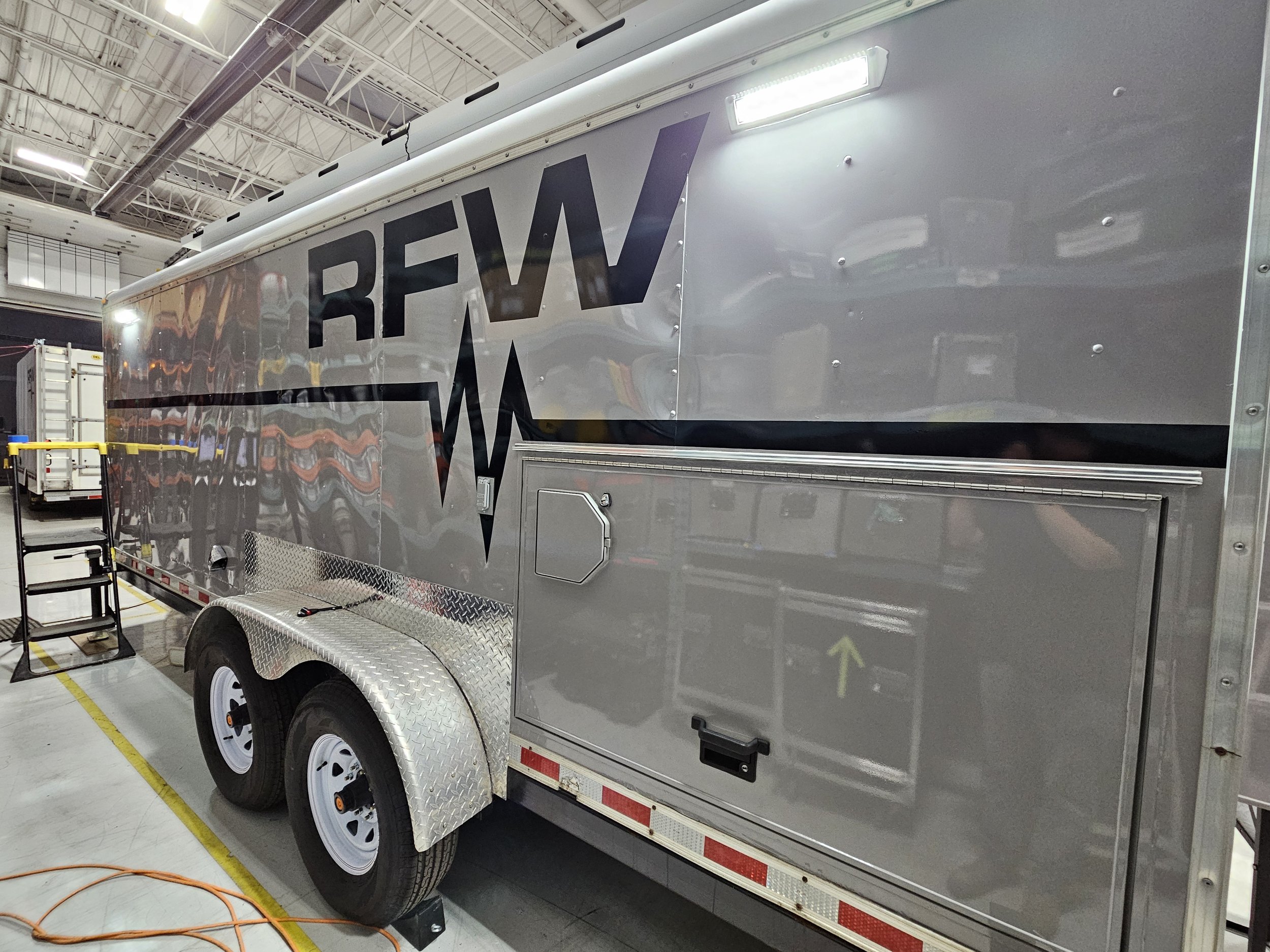 Emergency response trailer with RFM logo and medical symbol, inside a warehouse.
