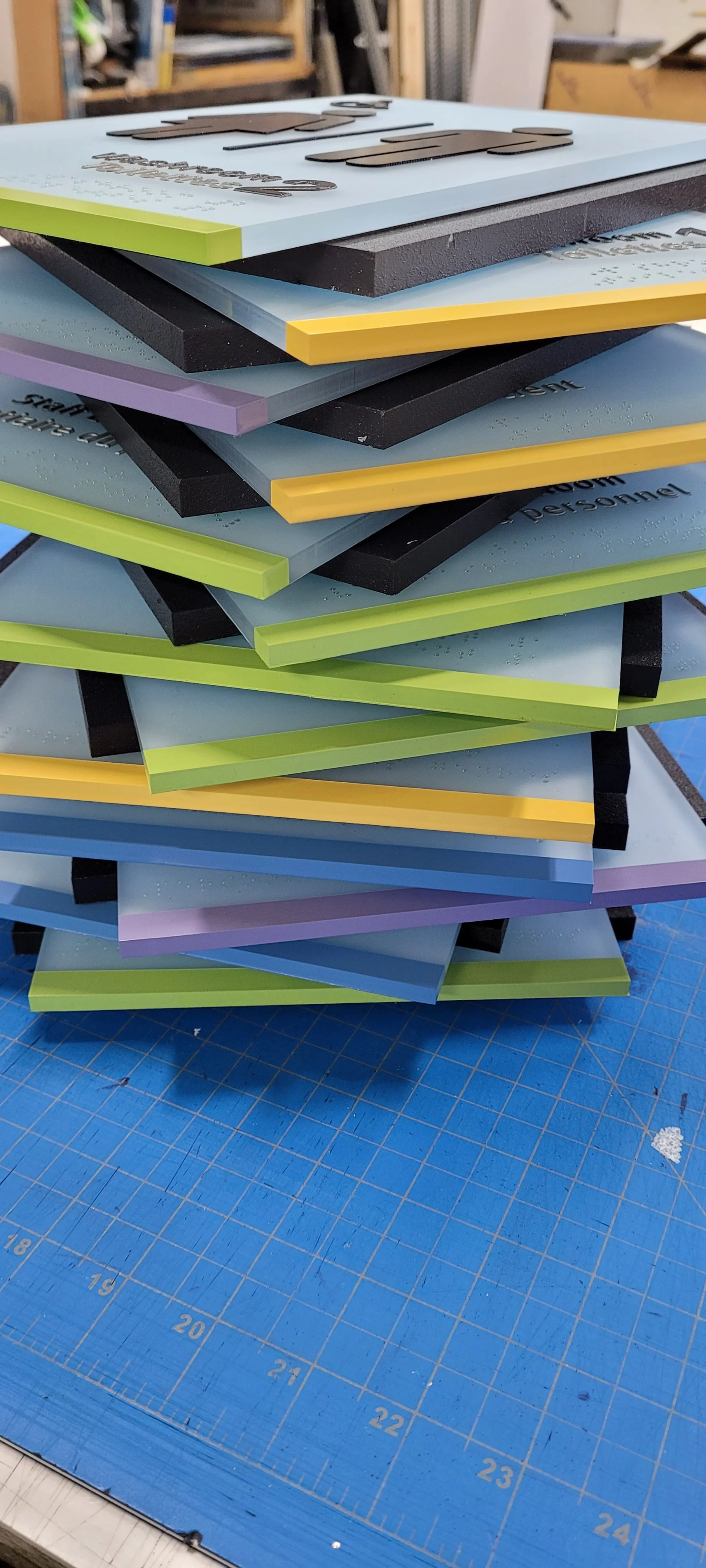 A stack of colorful foam boards on a blue cutting mat in a workshop.