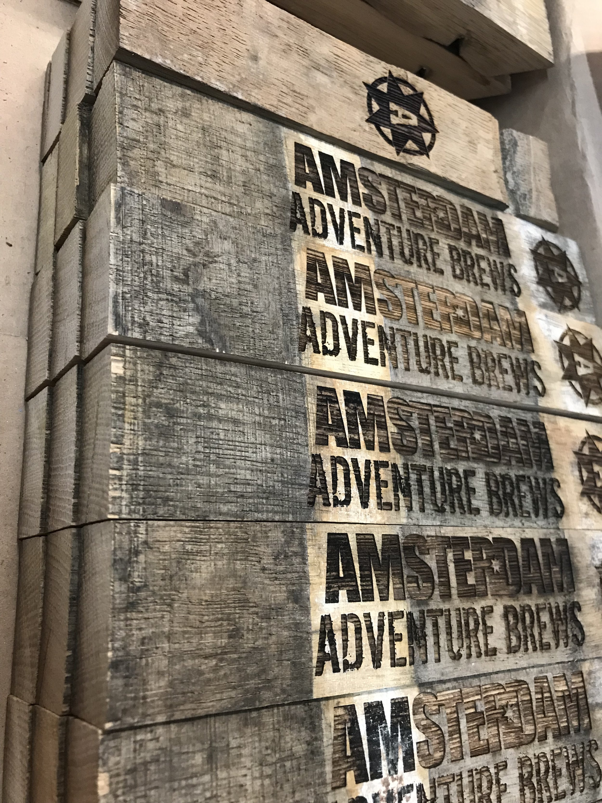 Stacked wooden boxes with printed text 'AMSTERDAM ADVENTURE BREWS' and star logos on the side.
