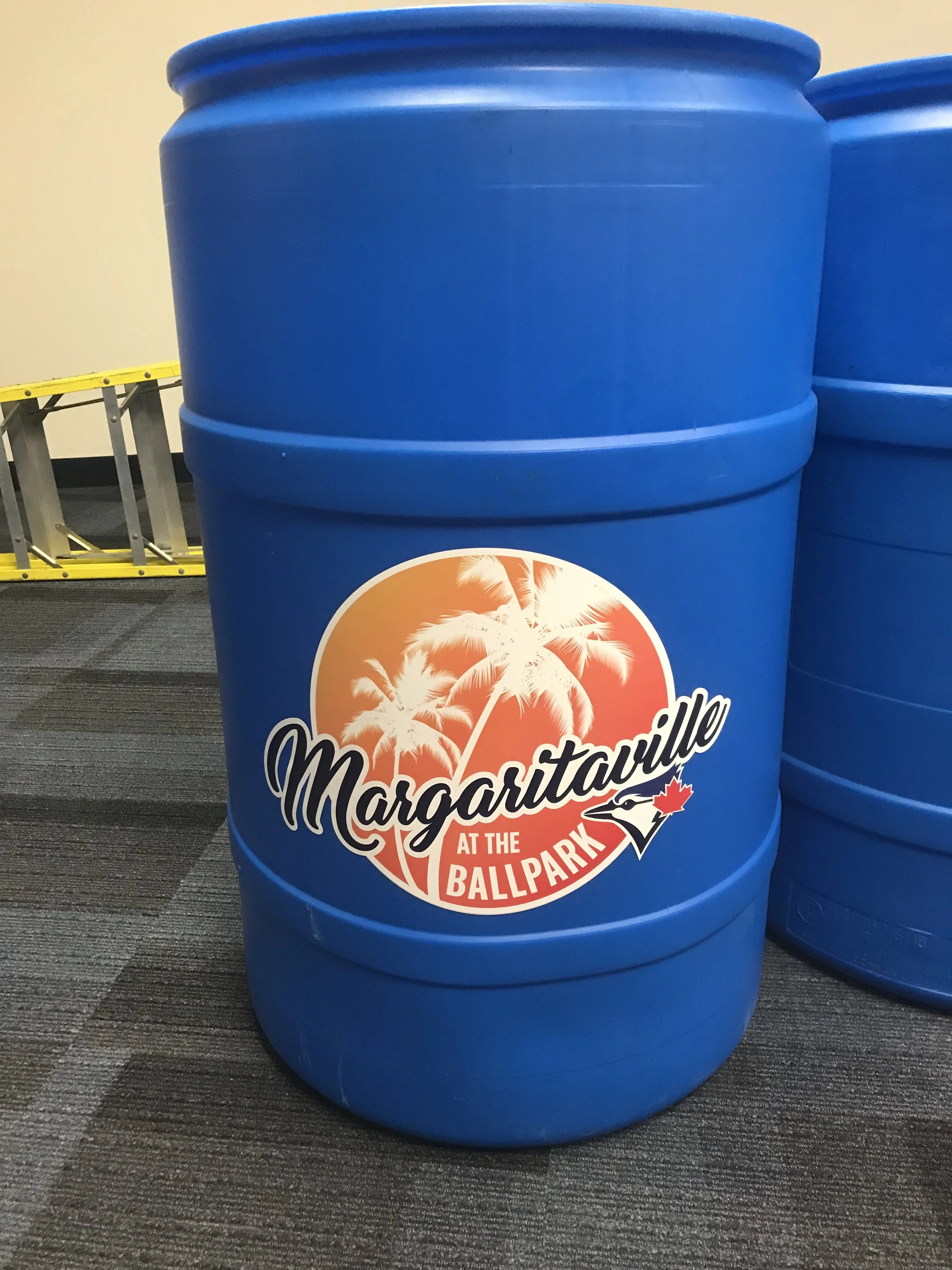 Blue barrel with a logo that features palm trees, a sunset, and the text 'Margaritaville at the Ballpark'.