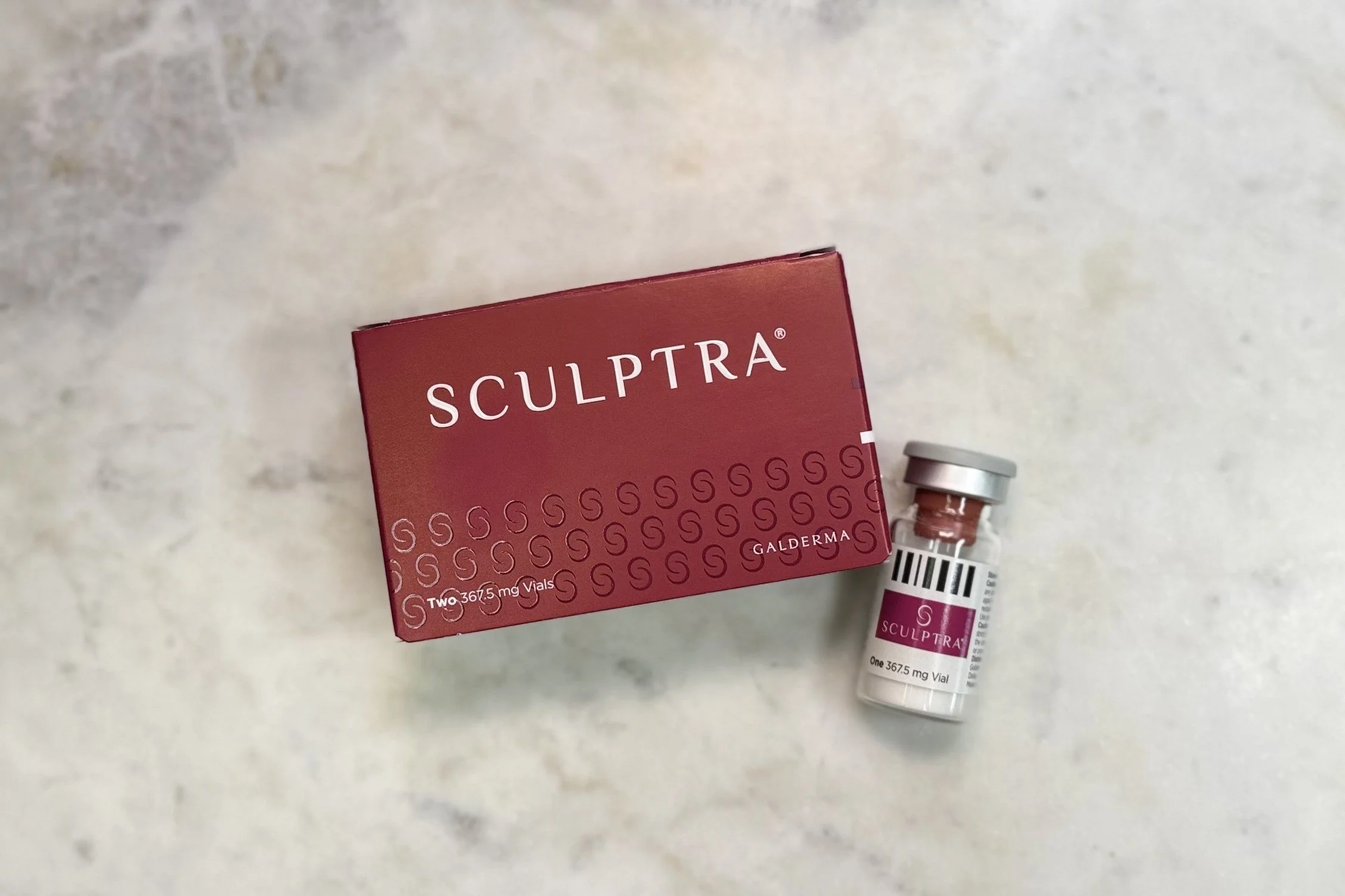 A box and vial of Sculptra, a skincare product, placed on a light-colored surface.