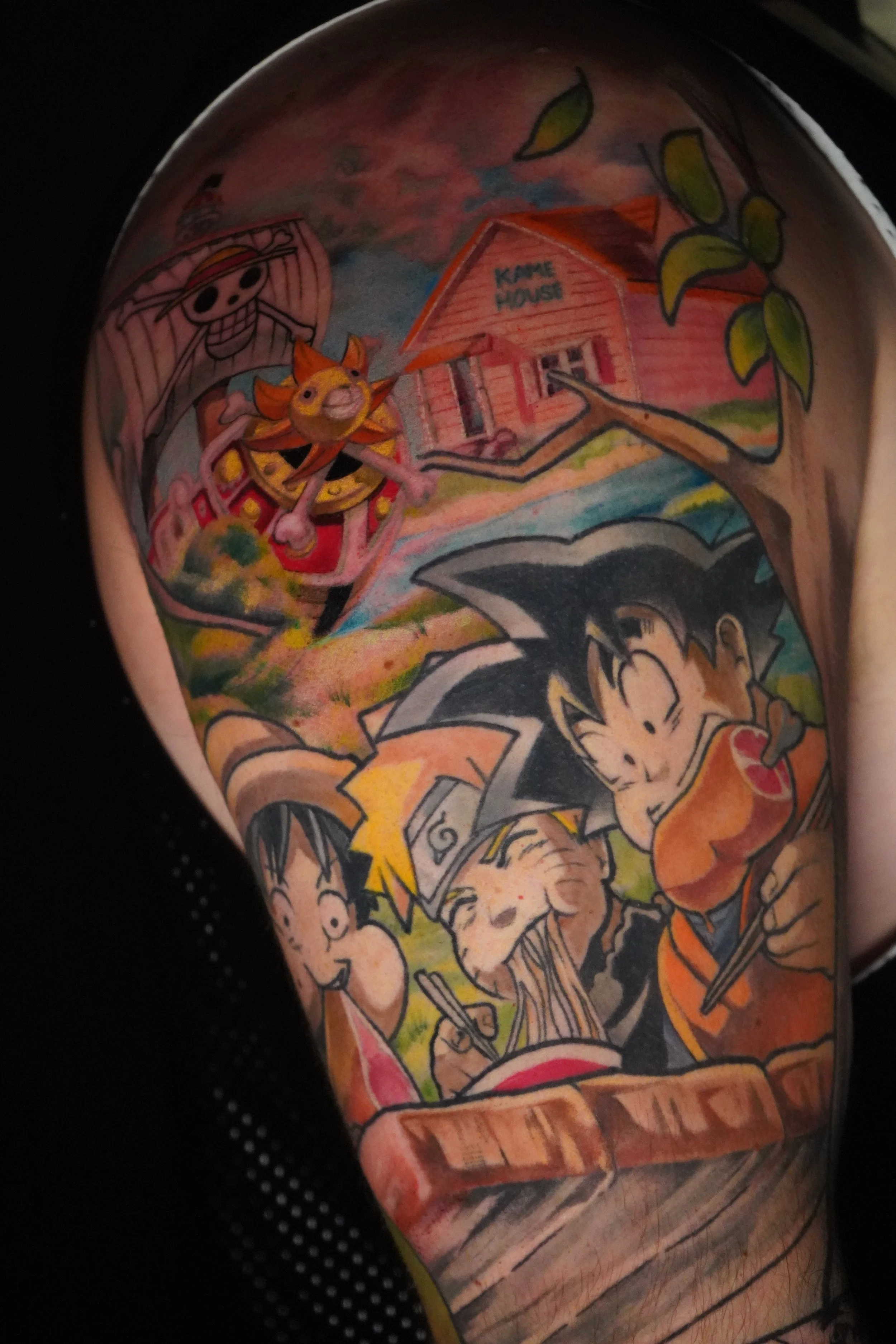 Colorful tattoo featuring characters from Dragon Ball Z eating, with a background of a house labeled 'Kame House' and a cartoon character on a skateboard.