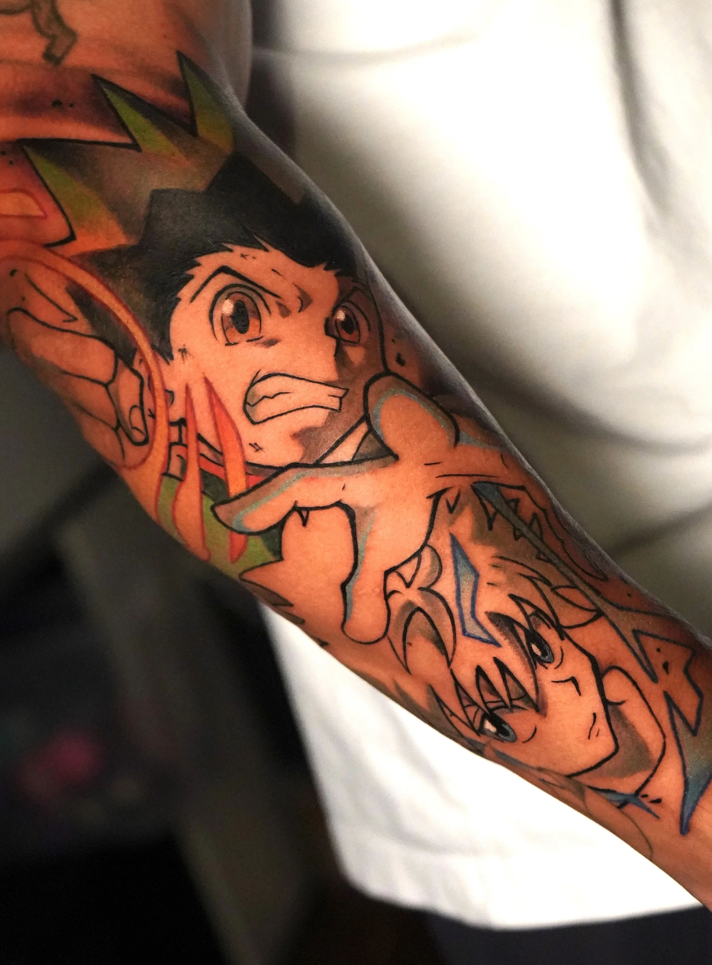 Tattoo of two anime characters with expressive faces on a person's arm.