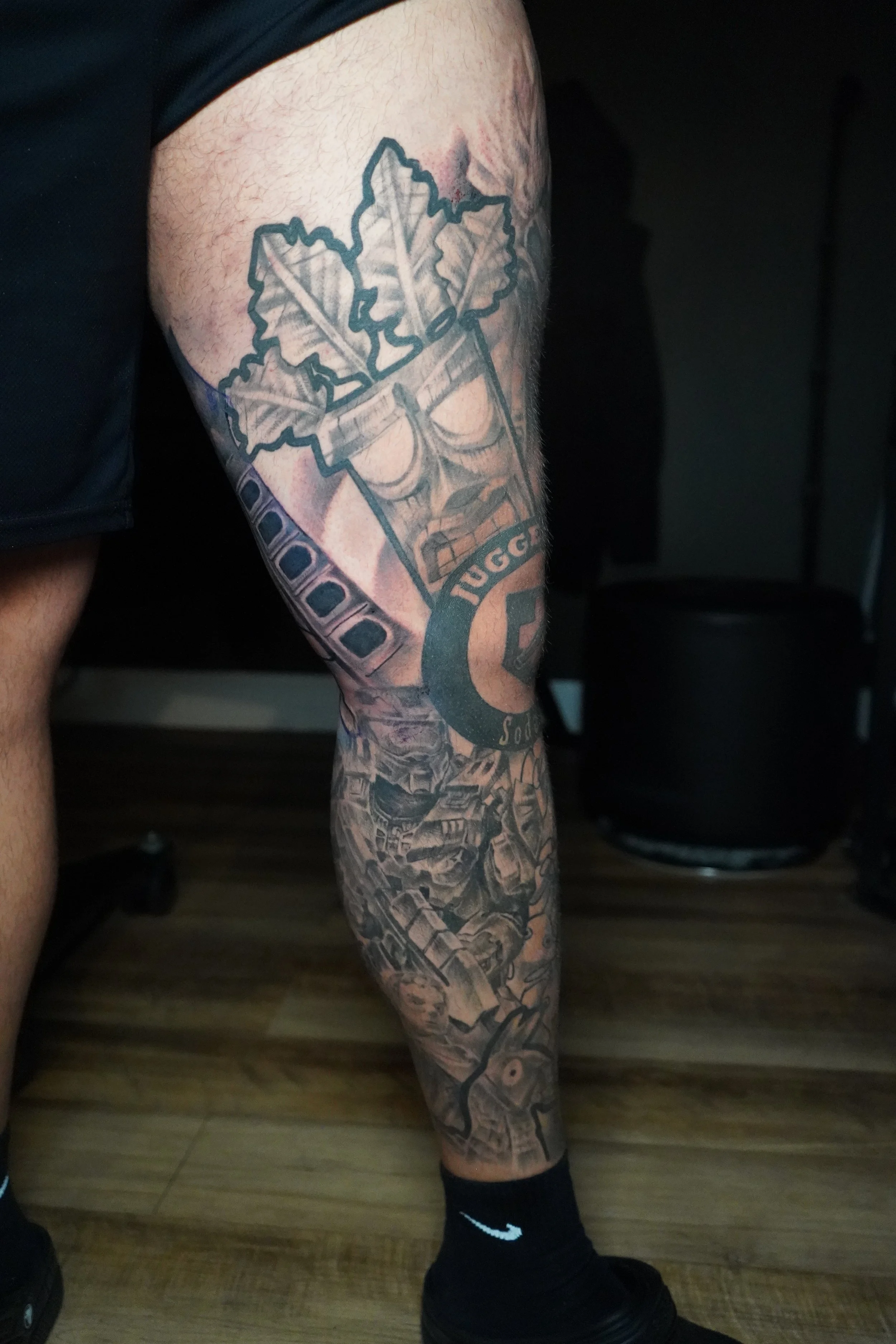 Tattooed left leg featuring leaf designs, a policeman badge, police vehicles, and police-themed motifs.