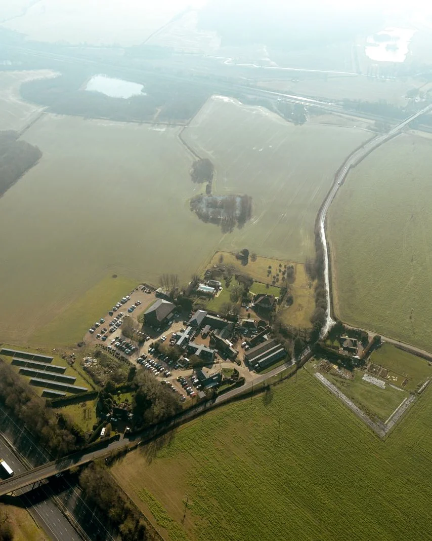 Aerial view of a rural landscape with fields, a farmstead, and a bridge over a road.