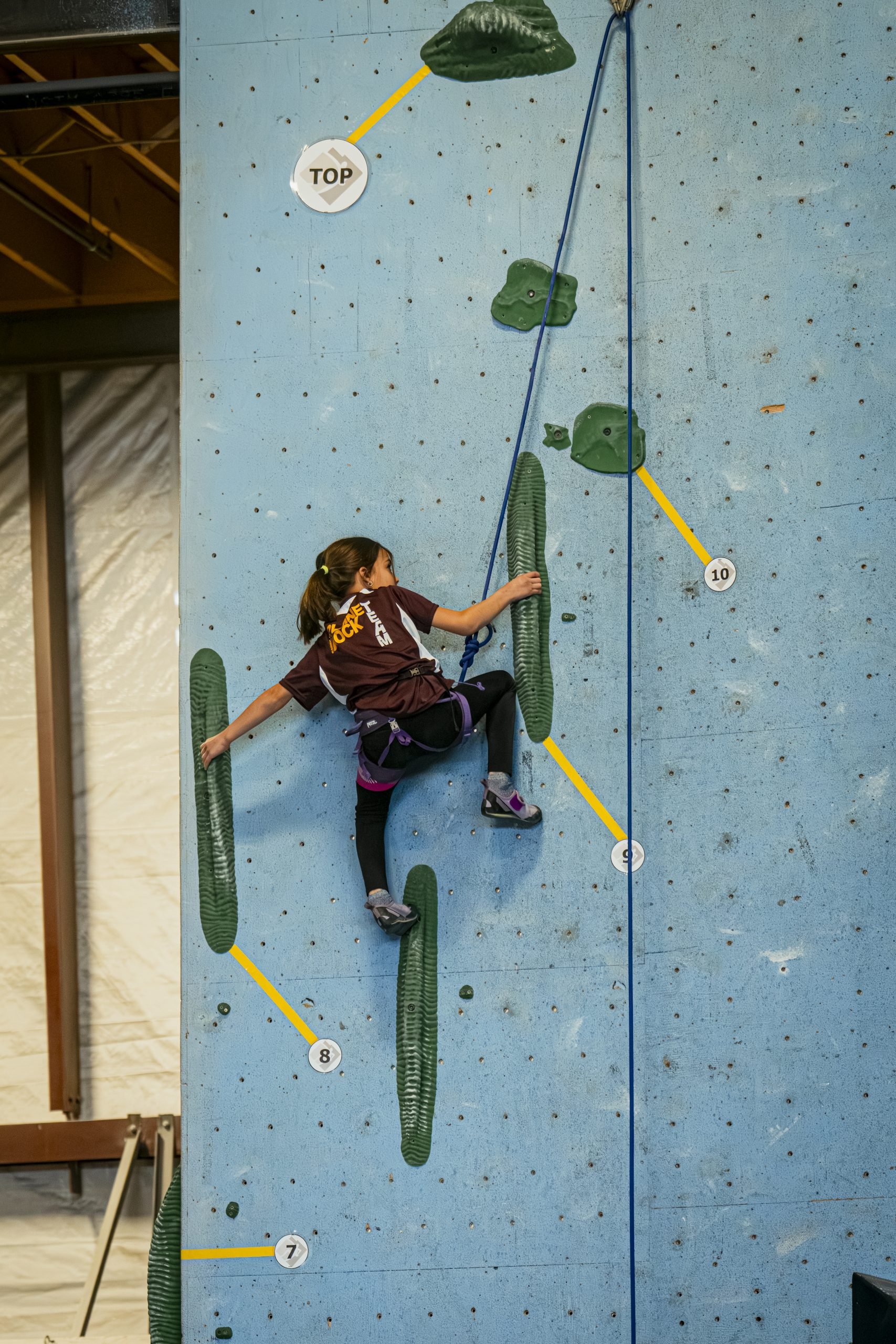 Youth team member climbing wall on top rope