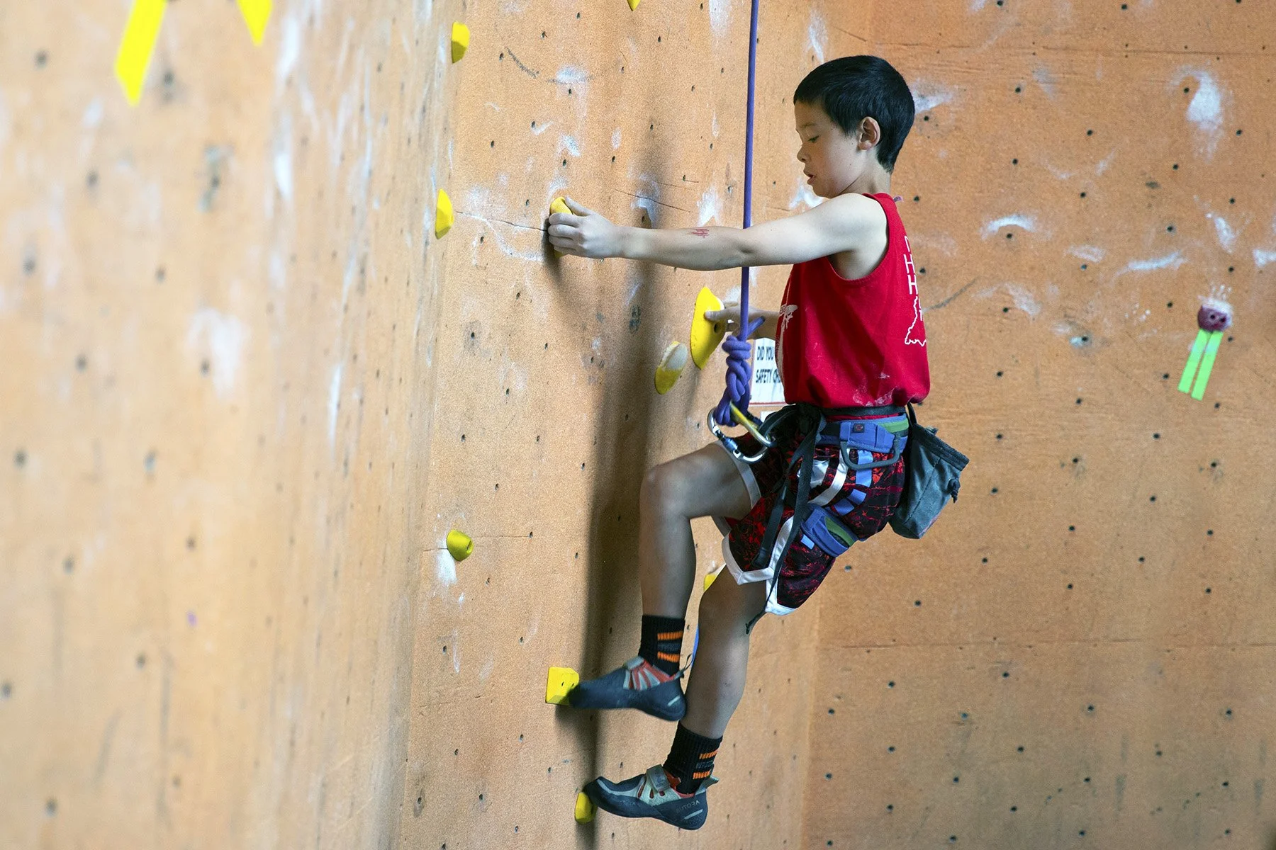 Child climbing wall at birthday party on top rope