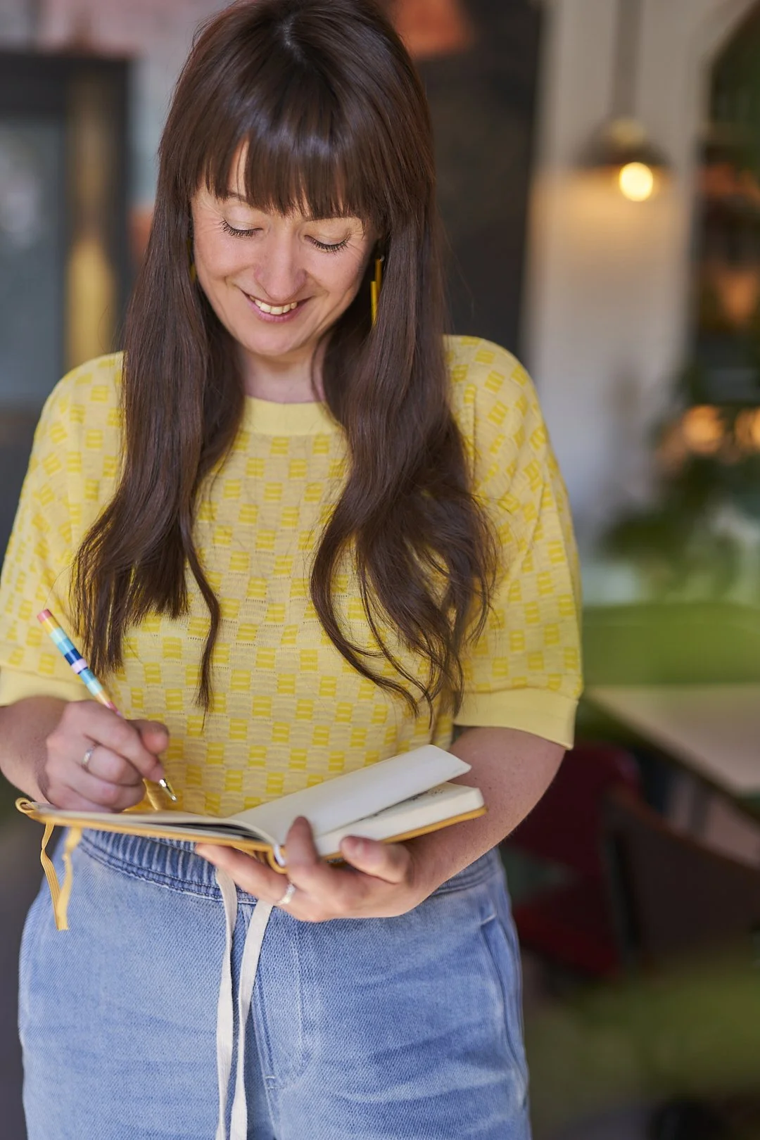 Leesa is standing up and writing in a notebook.