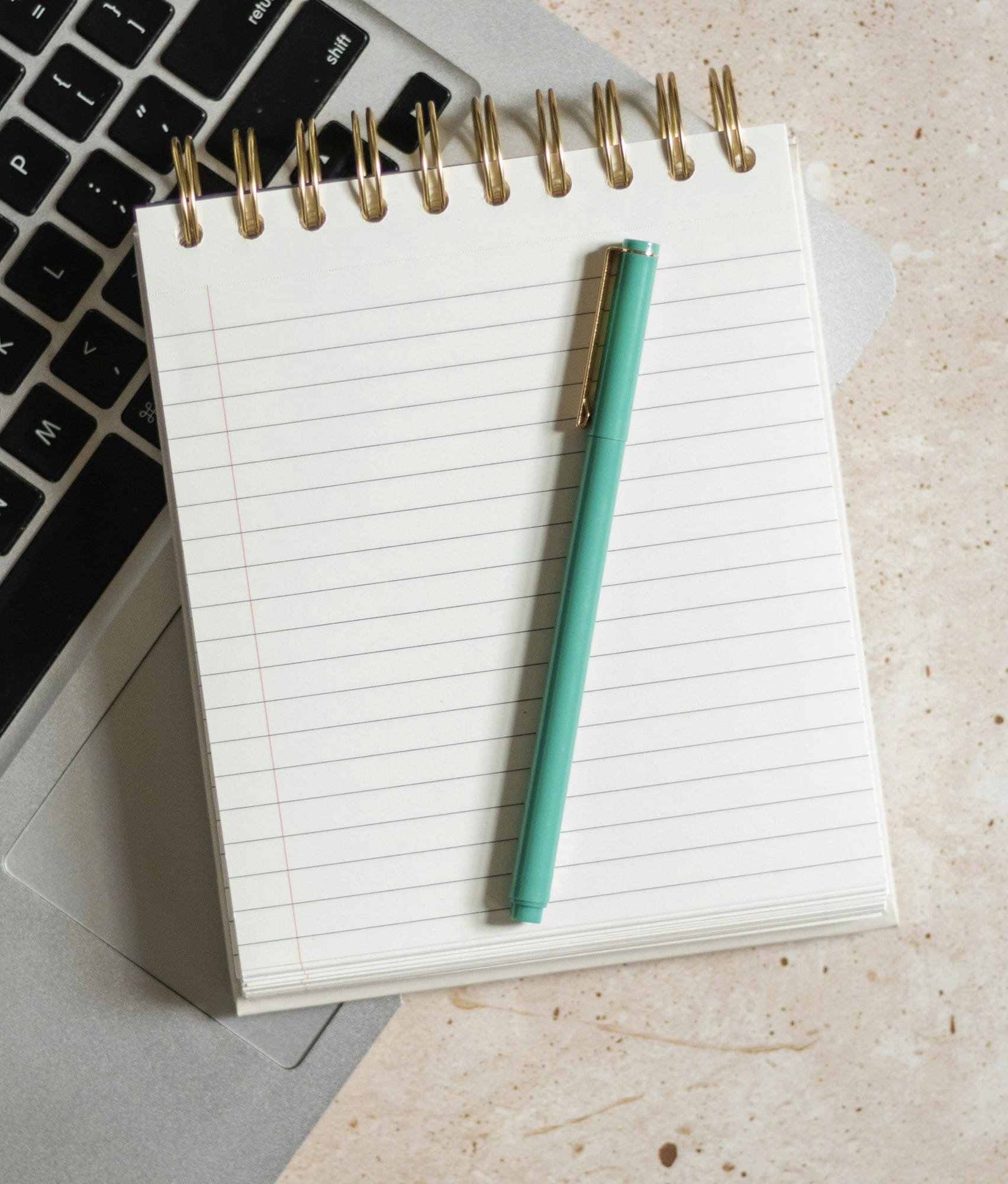 An open, empty notebook with a turquoise pen resting on top of it.