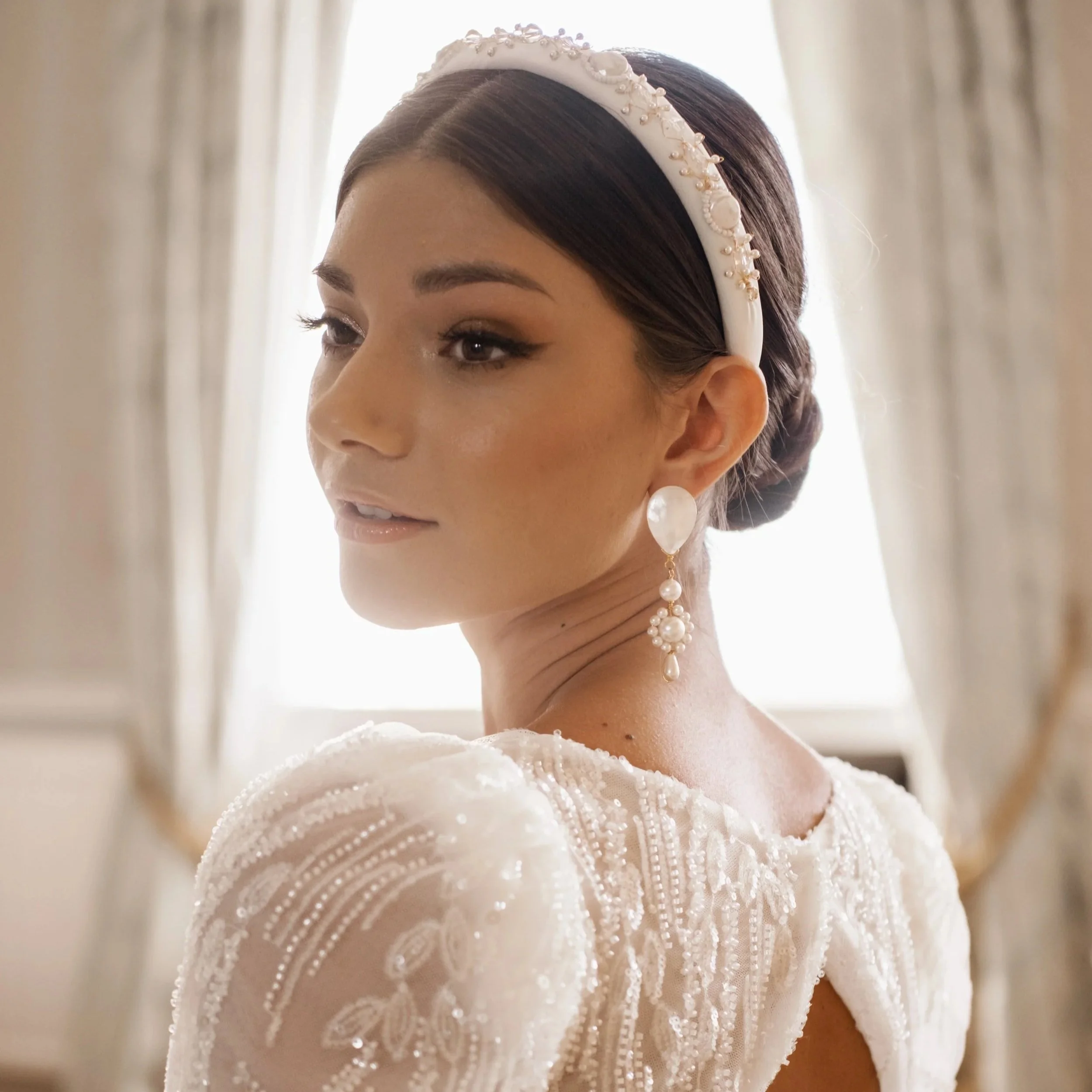 Bride wearing a couture pearl bridal headband and pearl earrings, showcasing refined bridal hair accessories designed to complement an elegant wedding dress.