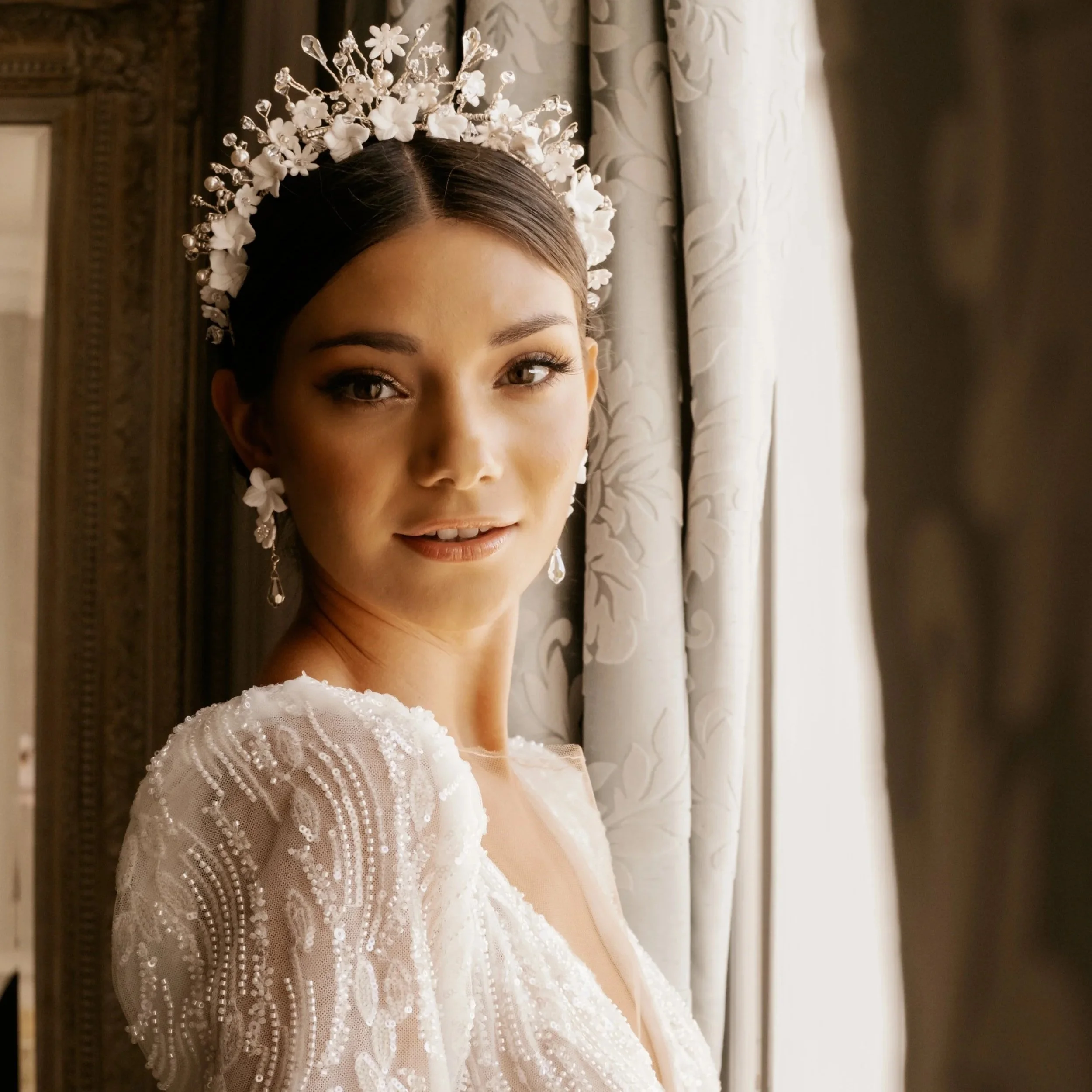 Bride wearing a couture floral bridal crown and pearl earrings, showcasing luxury bridal hair accessories designed to complement an elegant wedding dress.