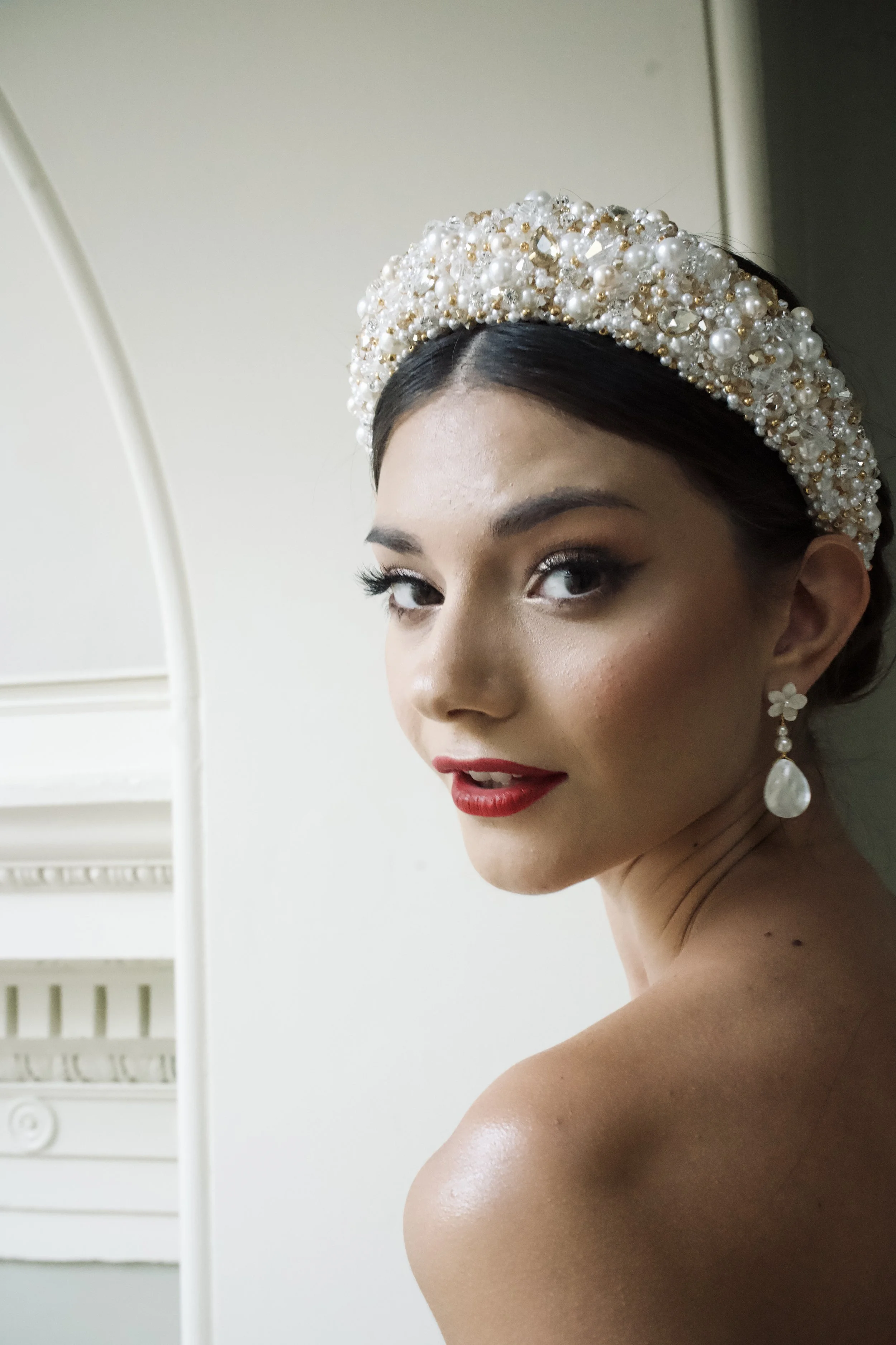 Bride wearing the couture Carmen beaded headband, an ivory pearl bridal headband handcrafted with intricate gold beading and the Sakura earrings for a modern couture wedding look.