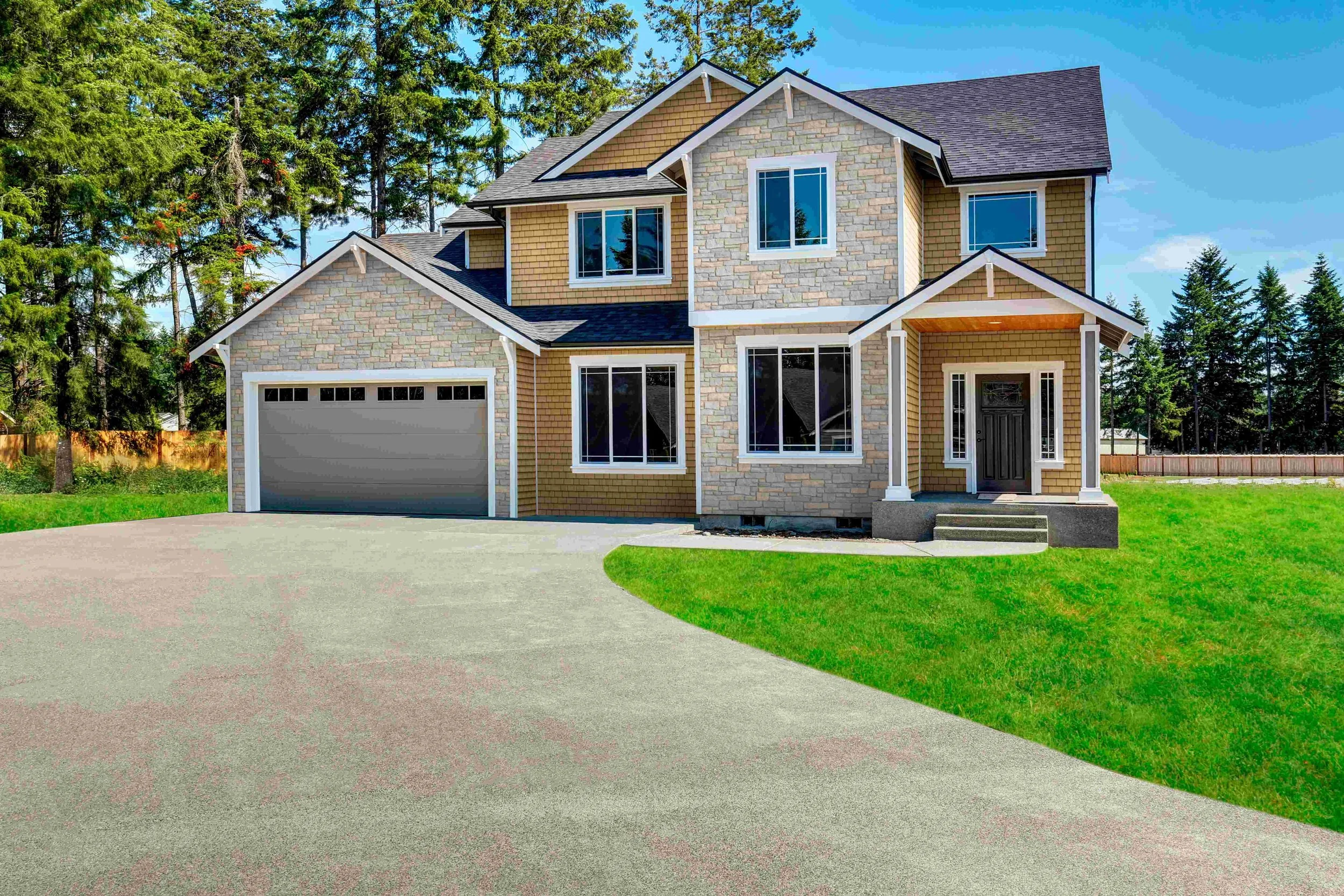 A modern two-story house with a stone and brick exterior, large windows, a front porch with steps, and an attached garage, surrounded by a well-maintained lawn and tall trees in the background.