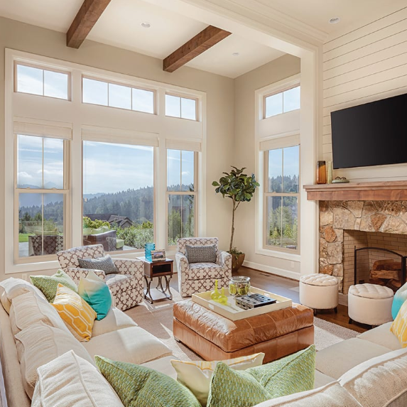 Bright living room with large windows showing a scenic mountain view, cozy furniture, and a fireplace.