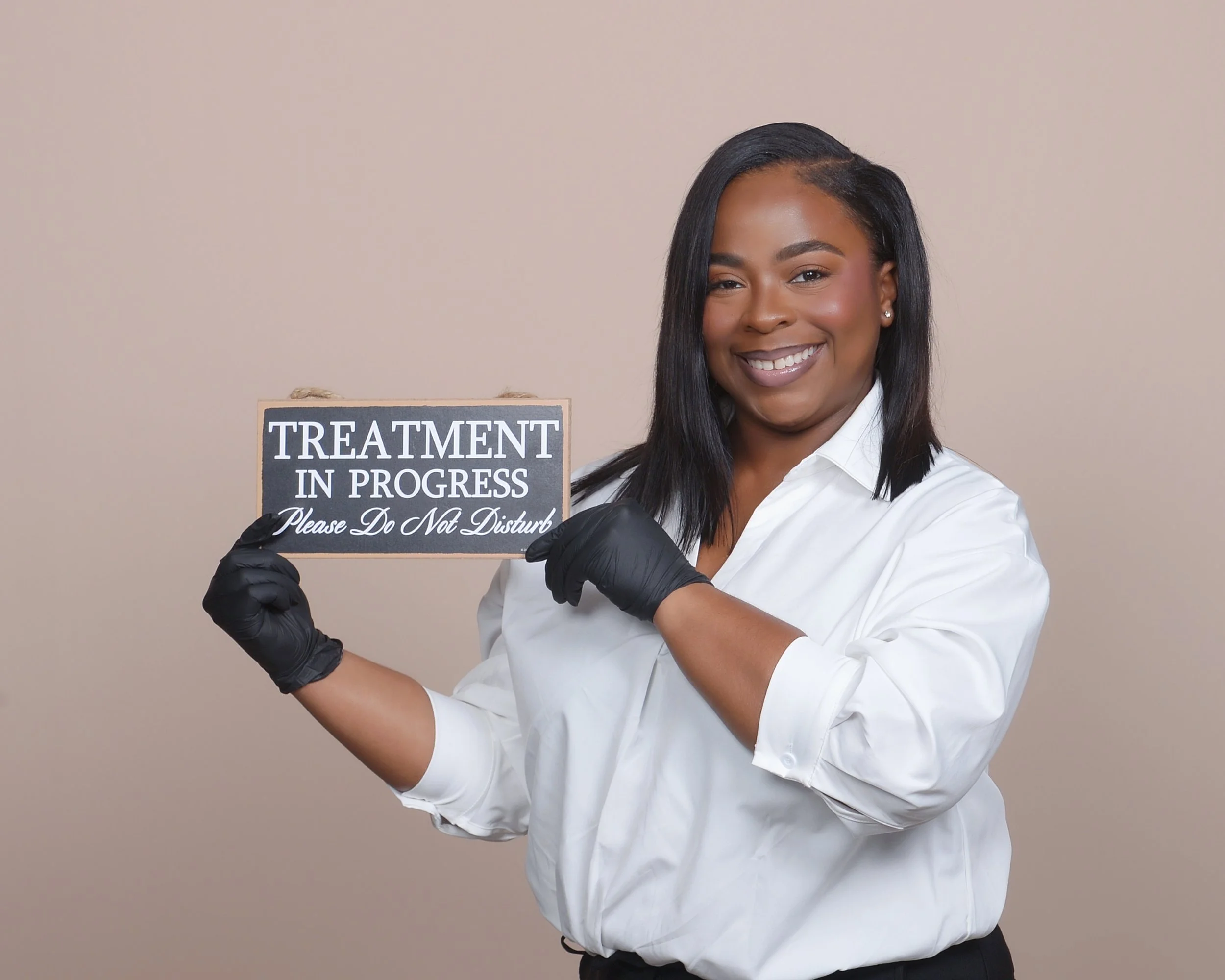 Licensed esthetician in Phoenix at AuraGlow Skinlab holding treatment in progress sign