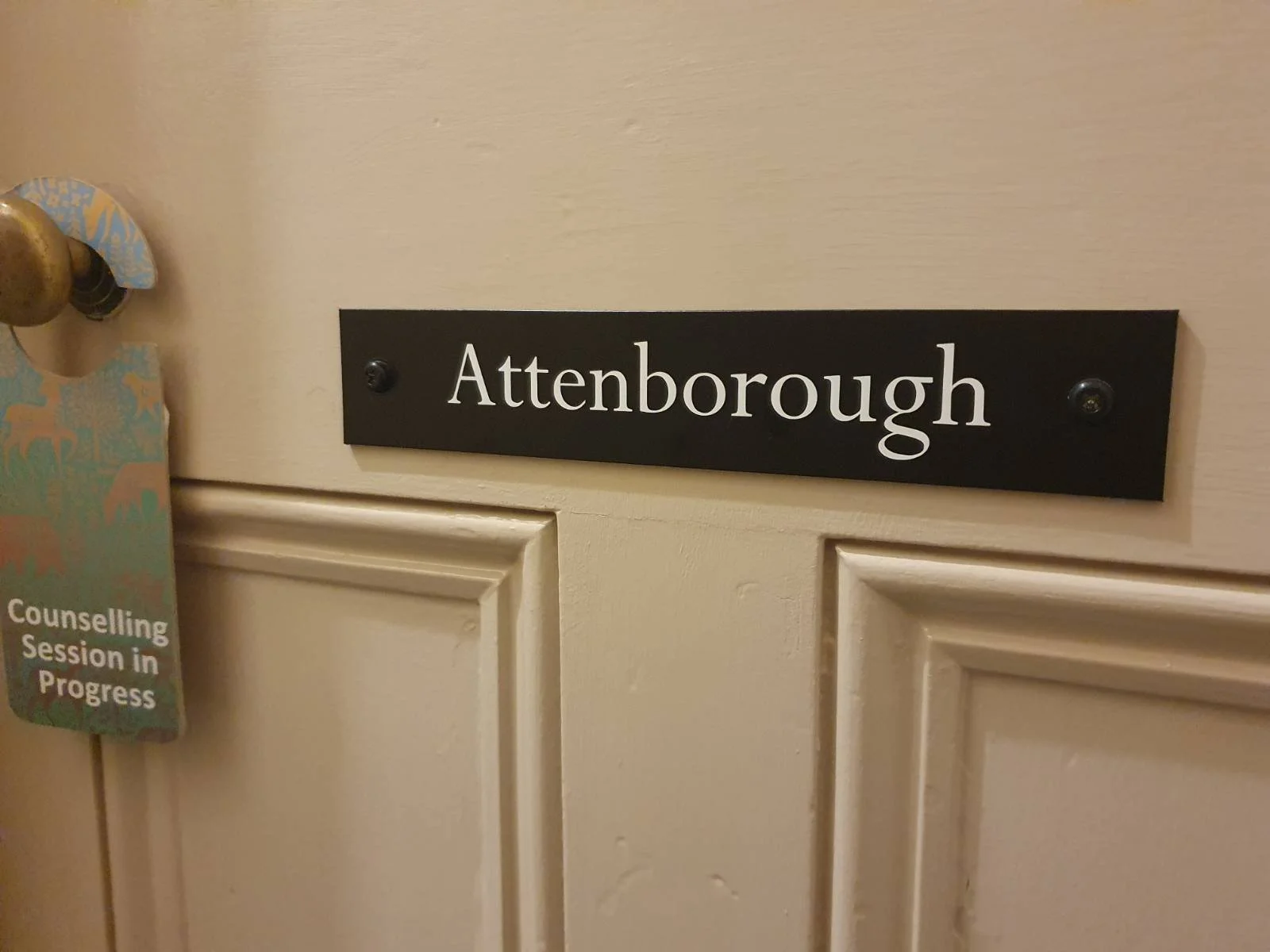 Door with a black nameplate reading 'Attenborough' and a notice tag about a counseling session in progress hanging on the doorknob.