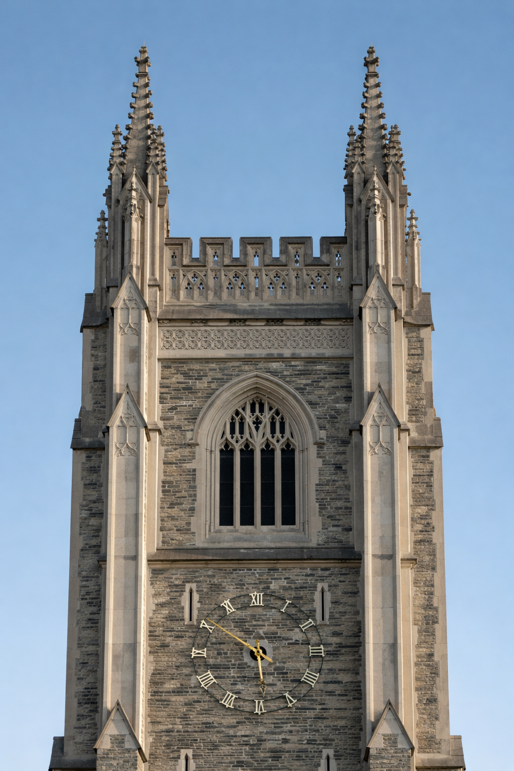 A tall Gothic-style church tower with a clock showing 4:22 and a clear blue sky in the background.