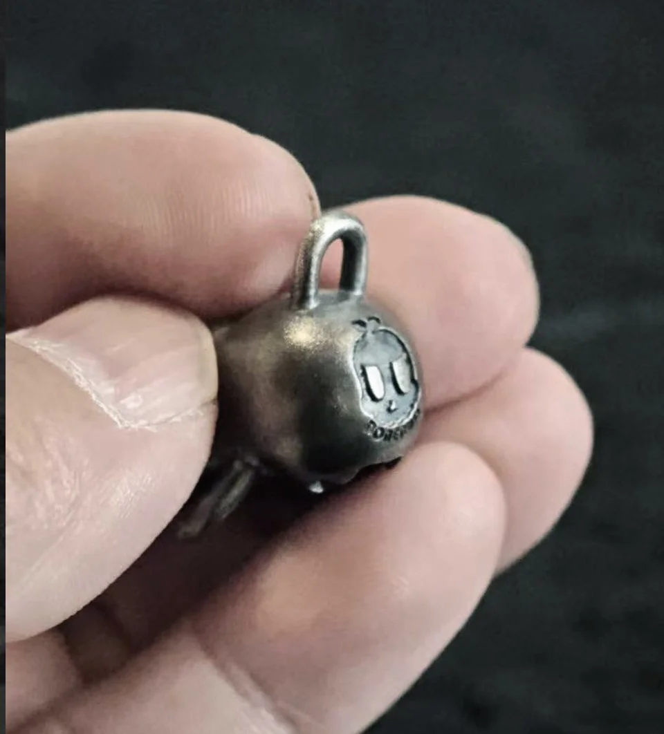 Xia Penghao BONE BUD THREE SENSES GAG Pendant - Handheld view showing BONE BUD logo on reverse
