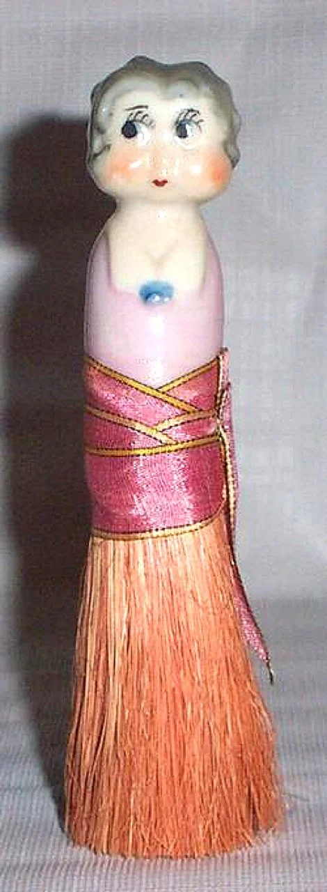 1930s Clothing Brush – The top half of this brush is made of ceramic lusterware; on the bottom is the broom. The bristles are held together with a silk band and slips into the bottom of the top piece. “Made In Japan” is printed on Betty’s back, but t