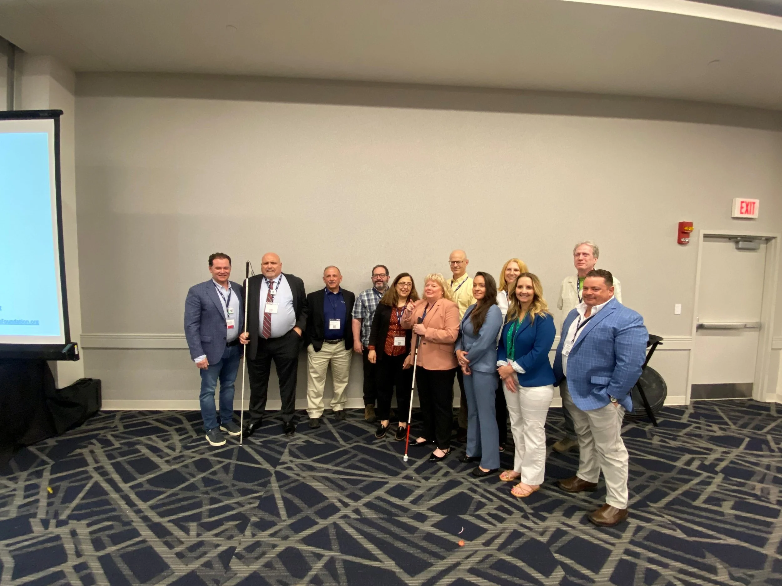the 2026 group of award winners posing together in a conference room, wearing name badges, with a projector screen showing a foundation website in the background.