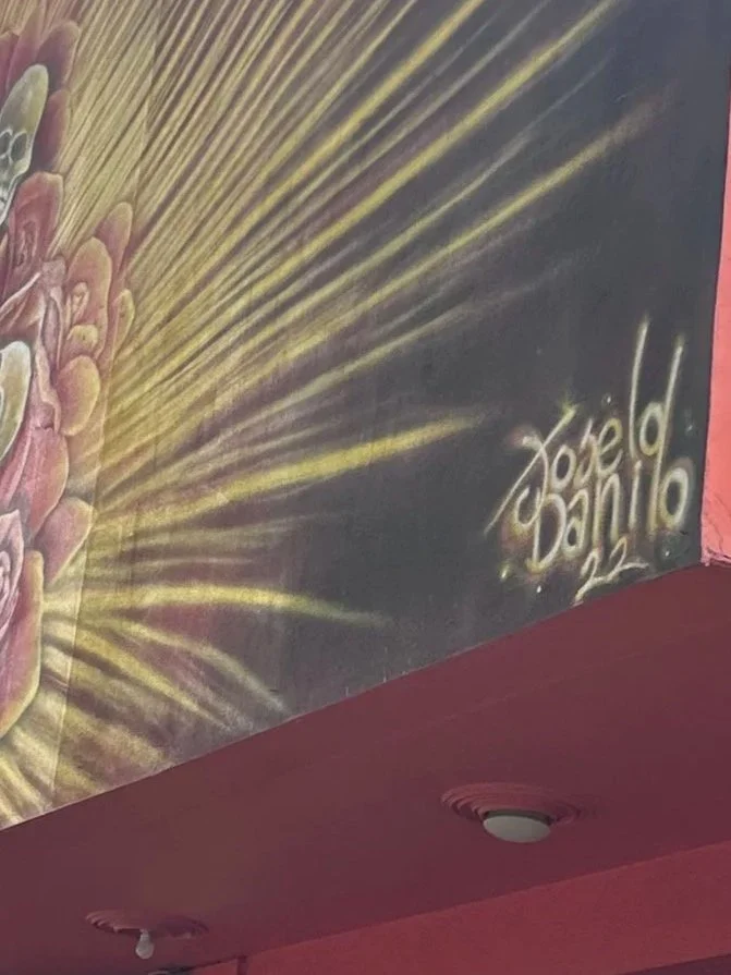 Graffiti on a wall with yellow rays and pink roses, signed by Joe D'Amico, 2020 in Medellín Colombia.