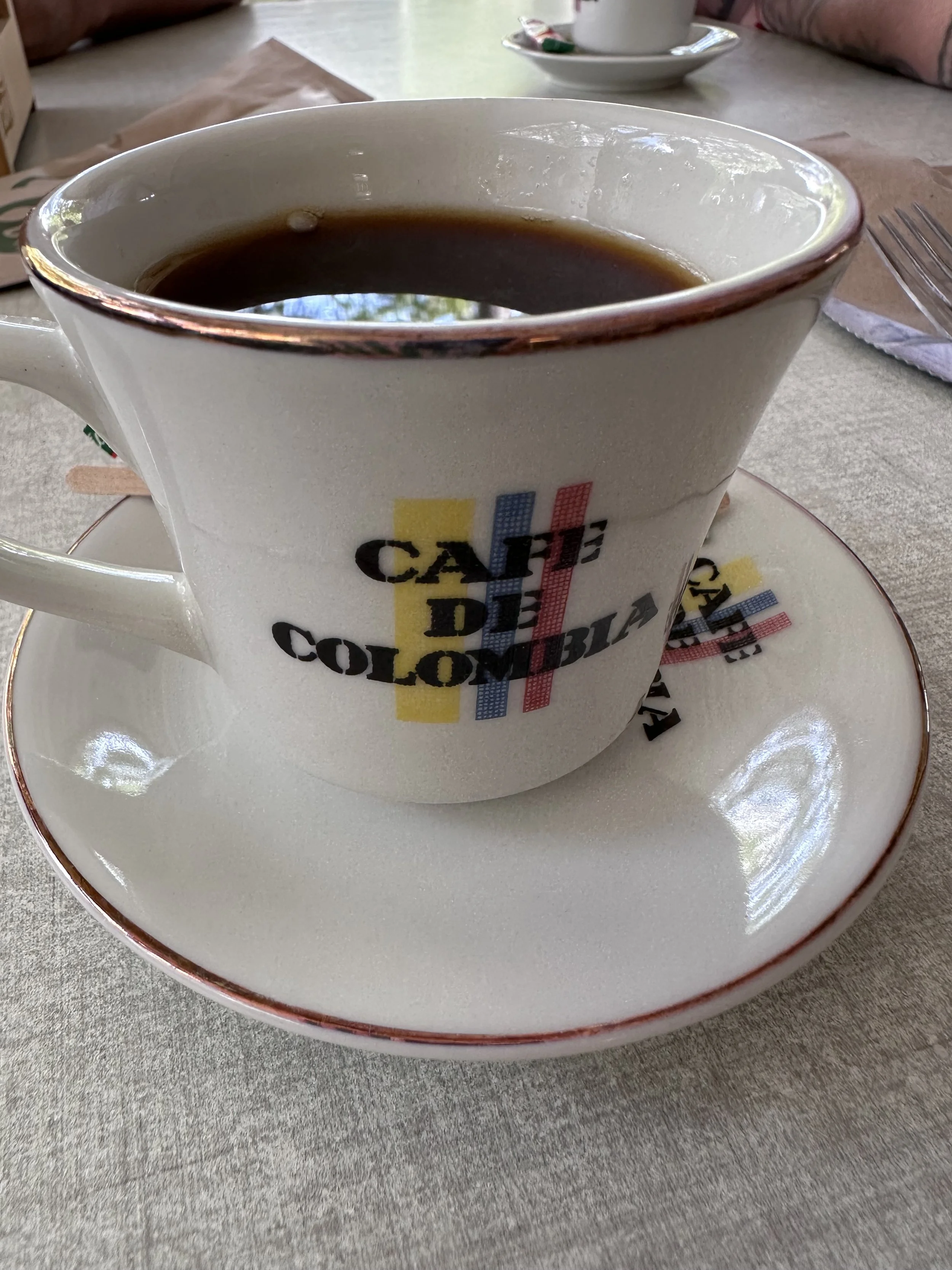 Close-up of a coffee cup filled with black coffee on a saucer, on a table in a cafe or restaurant setting. Coffee cup photographed in Santa Marta in Colombia.